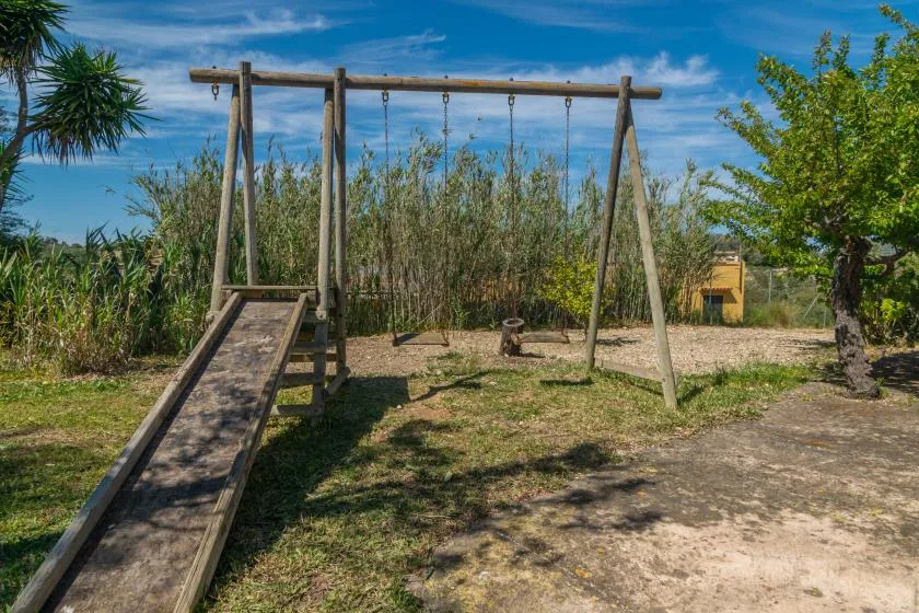 An outdoor playground has a wooden swing set and a slide.