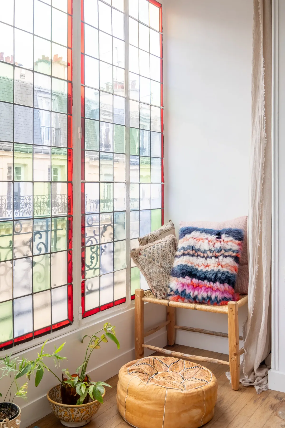 Un rincón junto a la ventana con cojines coloridos y plantas en macetas.