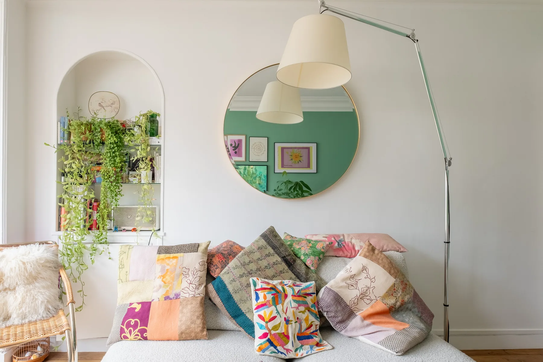 Una colorida zona de estar ocupa la sala, bajo un espejo redondo y lámparas colgantes.