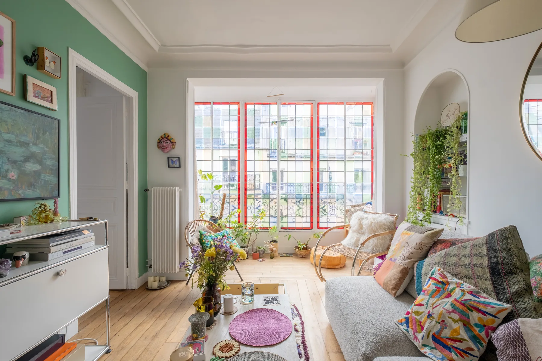 A bright living room with seating, colorful cushions, and large windows.