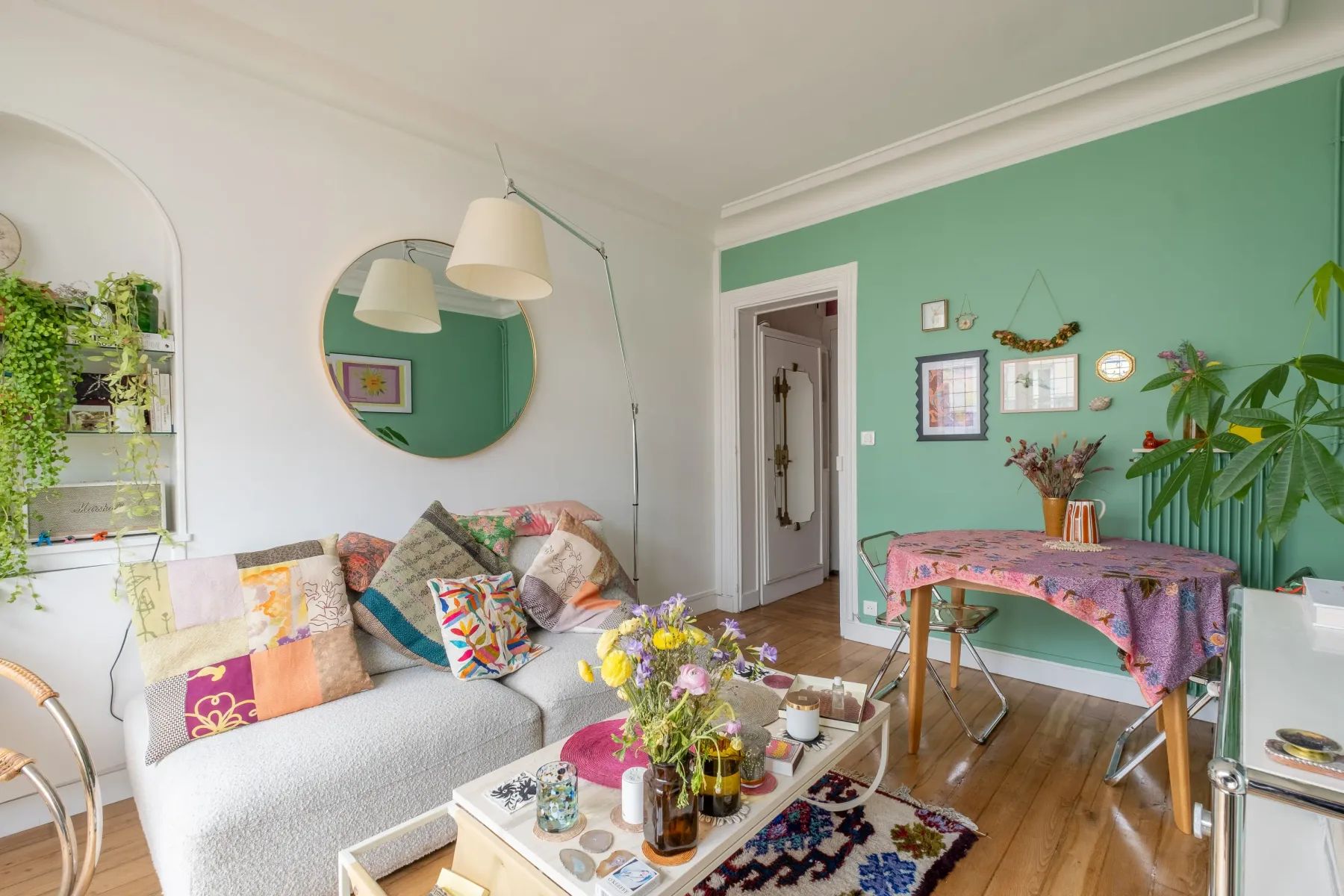 Un salón colorido con asientos, un espejo redondo y una mesa de comedor.