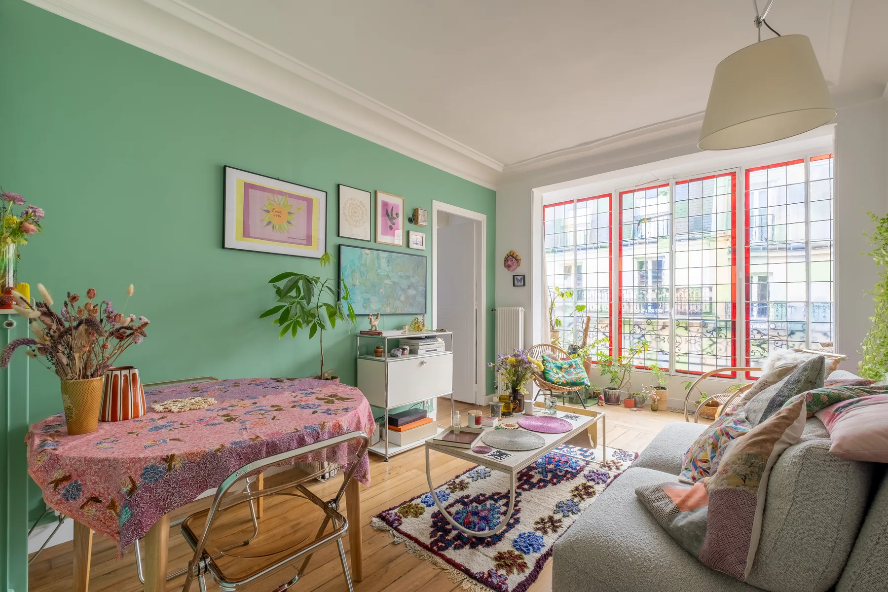 Una sala colorida con una mesa de comedor, asientos y grandes ventanas.