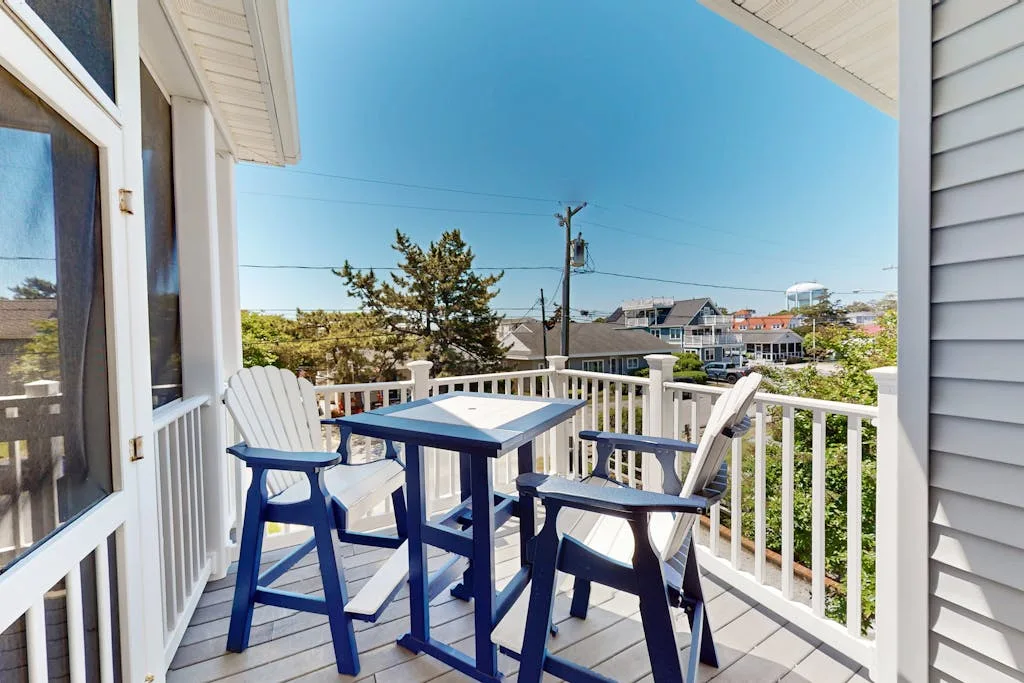 A small balcony with blue outdoor seating and views of nearby rooftops.