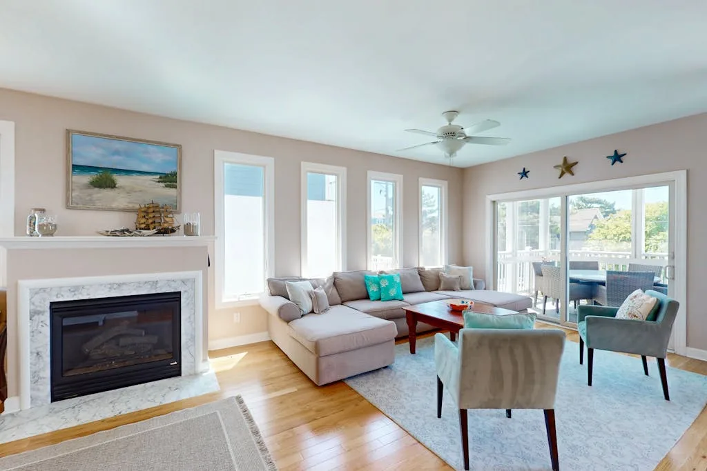 A bright living room with a sectional seating area, fireplace, and large windows.