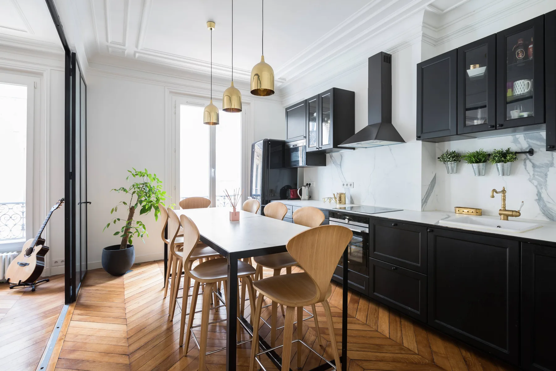 Una cocina y comedor luminosos con muebles oscuros y una mesa larga.