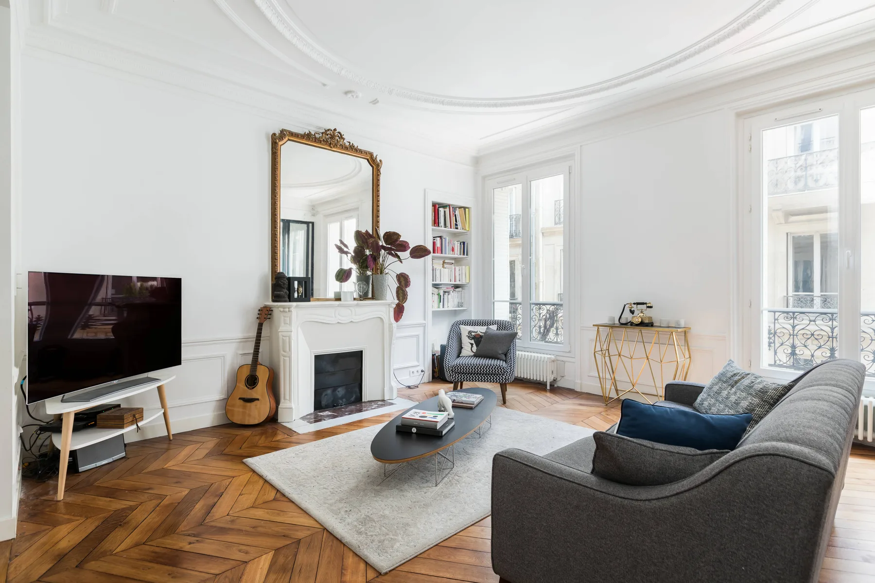 Una sala de estar luminosa con chimenea, asientos y ventanas altas.