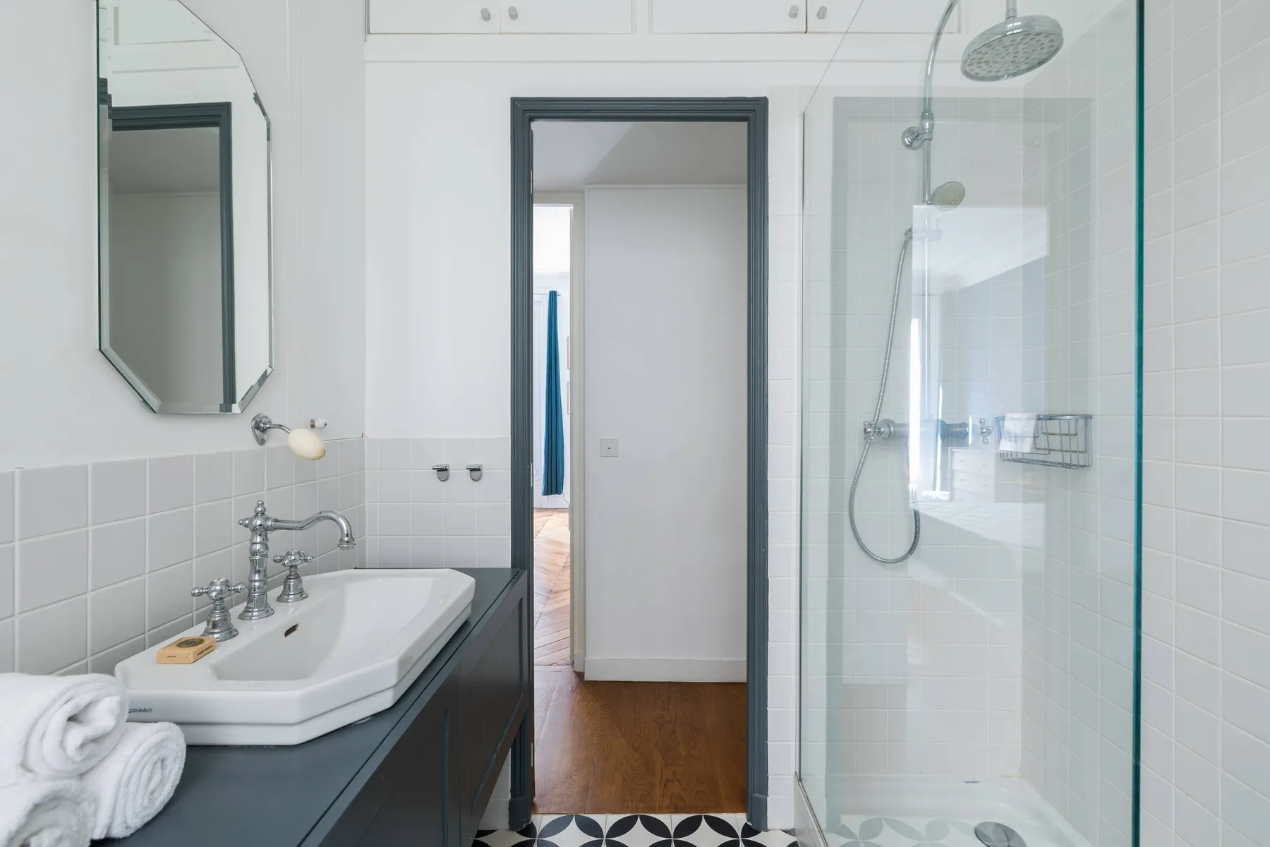 A bright bathroom with a sink vanity beside a glass shower.