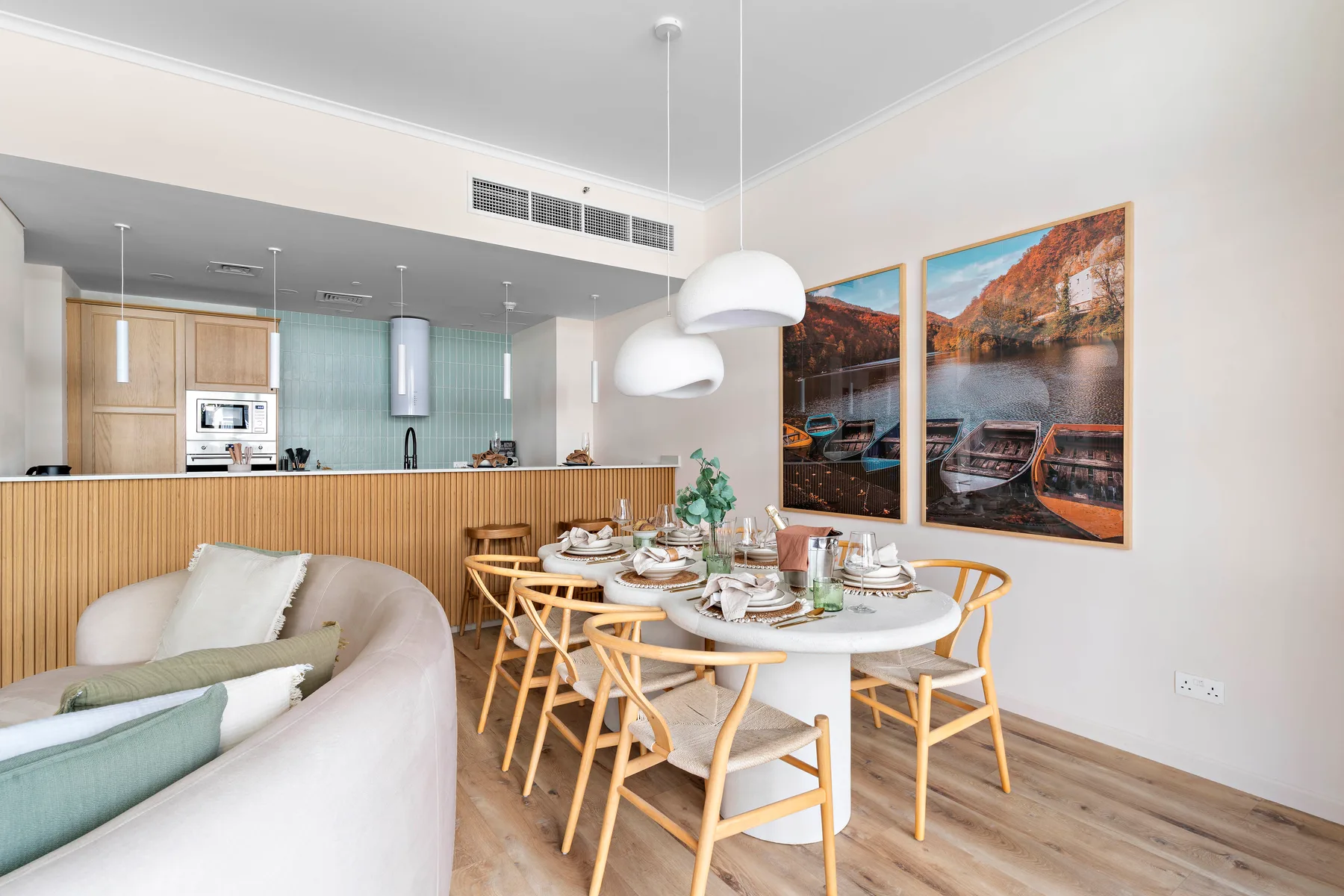Comedor de planta abierta con la mesa puesta junto a una cocina y cuadros.