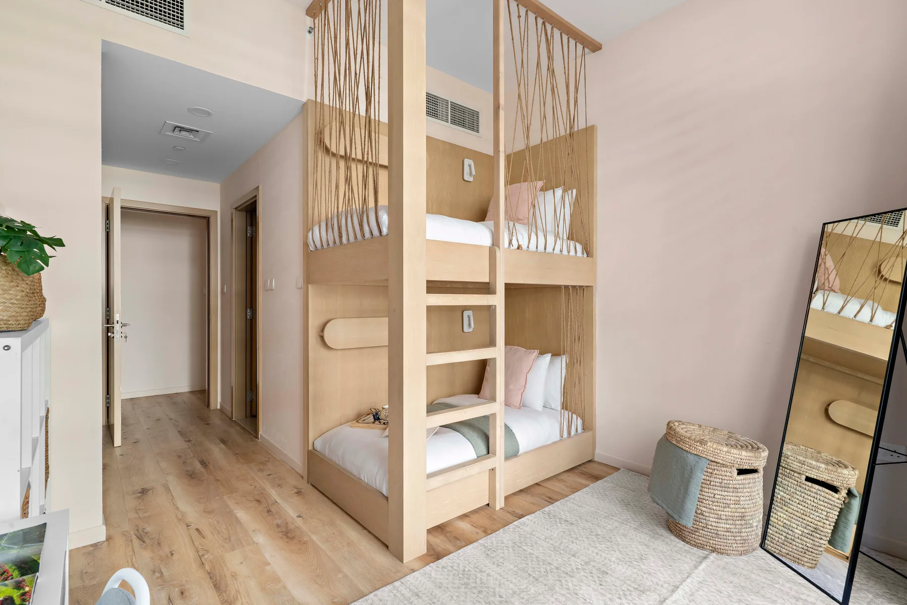 Un dormitorio con literas de madera y una alfombra de color claro.