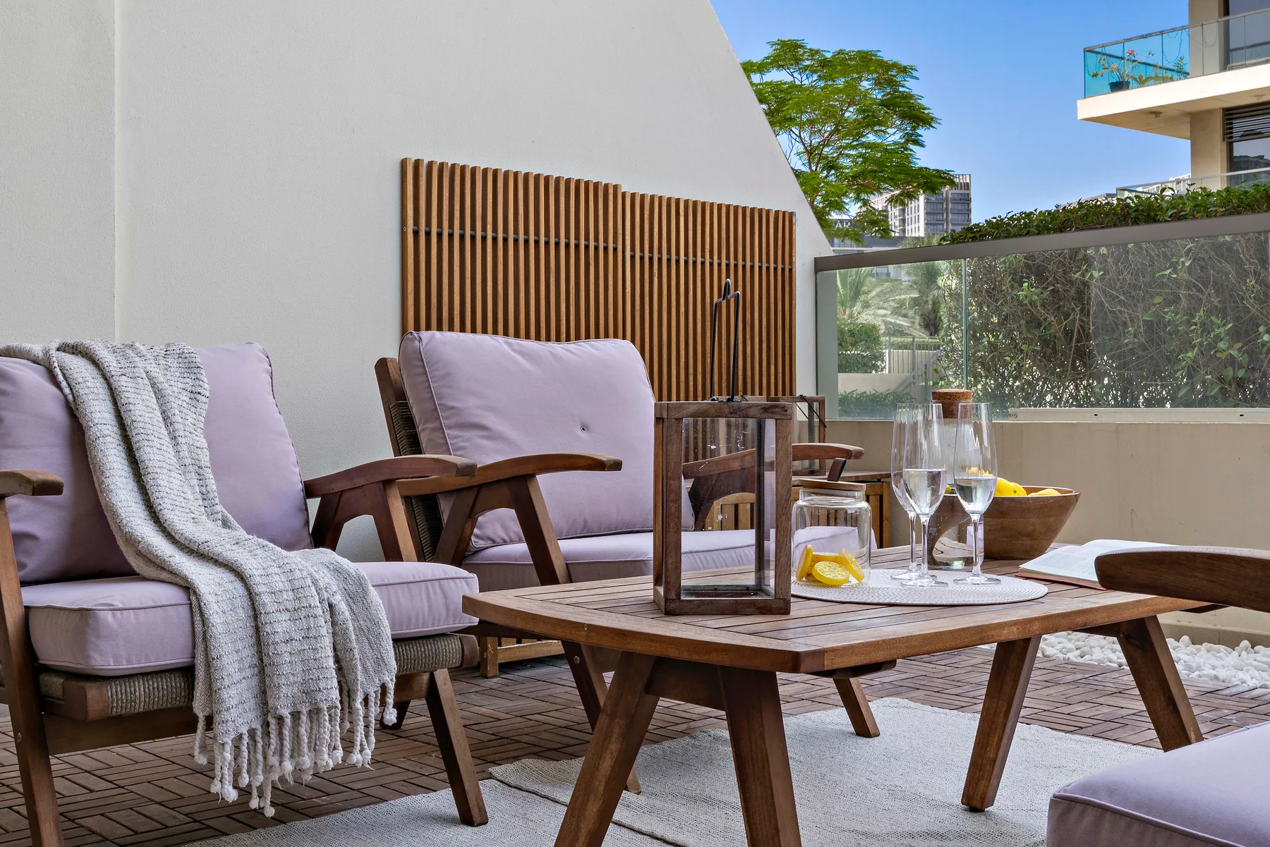Una zona de estar al aire libre con asientos acolchados y una mesa baja de madera.
