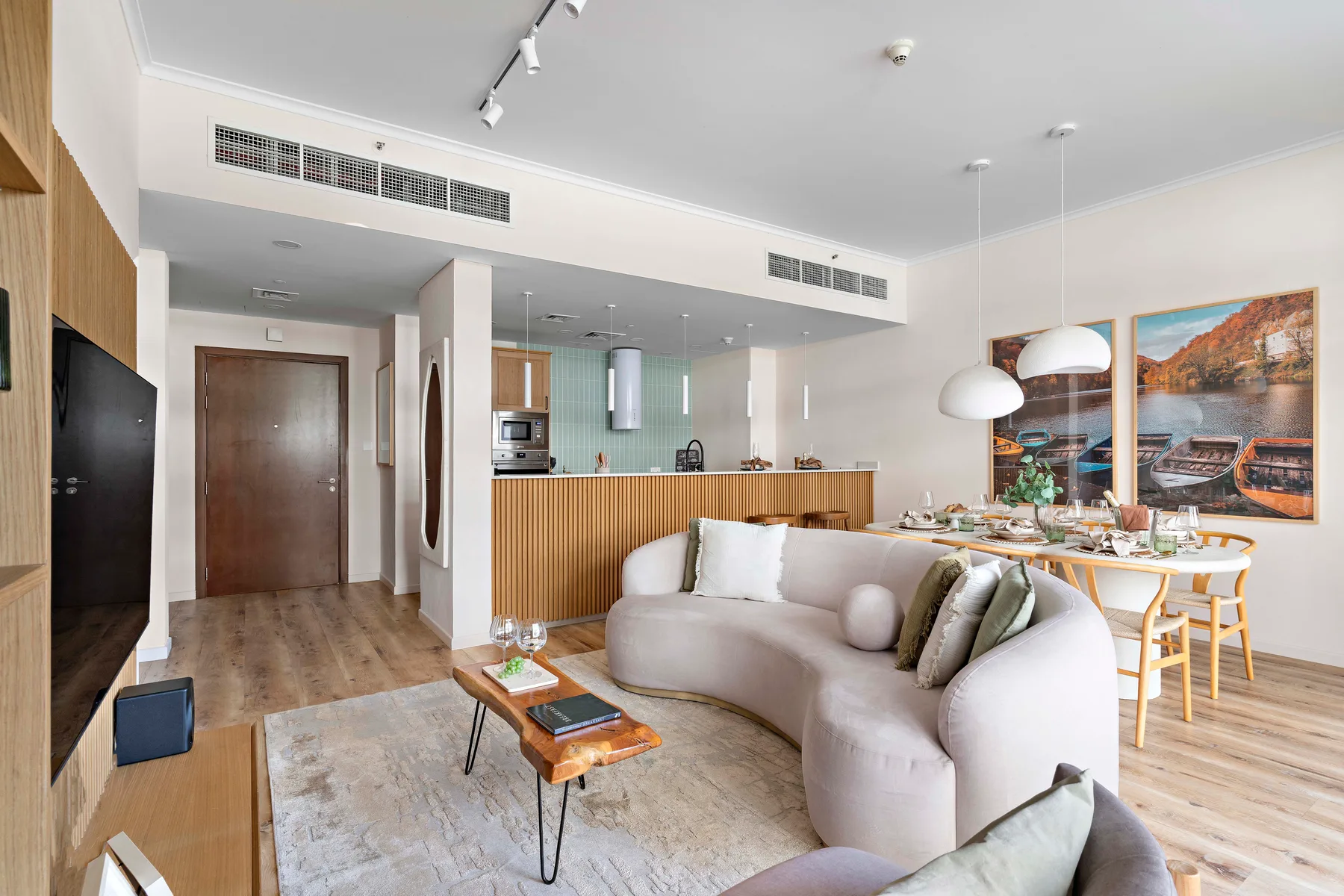 Una luminosa sala-comedor diáfana con un sofá curvo y una mesa de comedor.