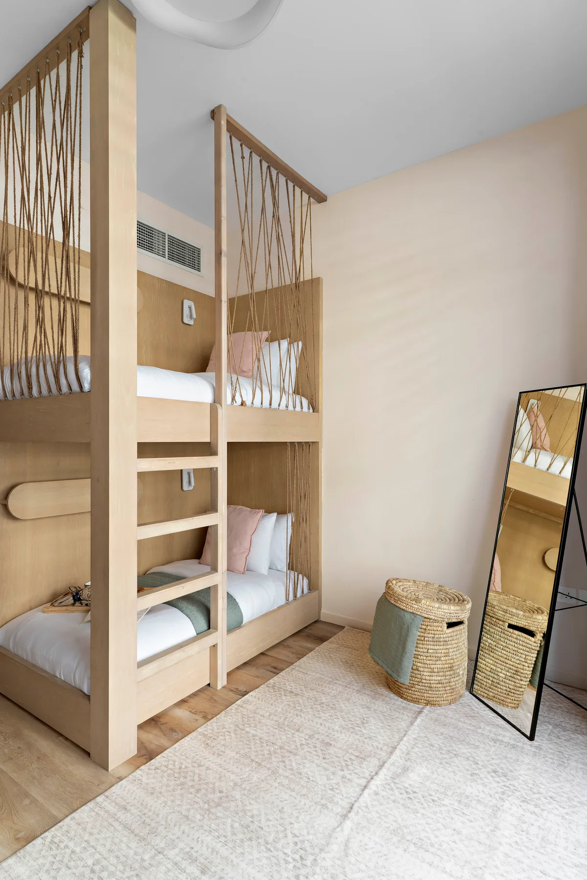 Un dormitorio con literas integradas, pantallas tejidas y un espejo de cuerpo entero.