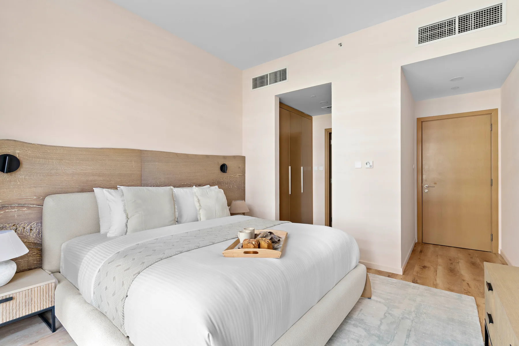 Un dormitorio luminoso con una cama bien hecha y ropa de cama clara.