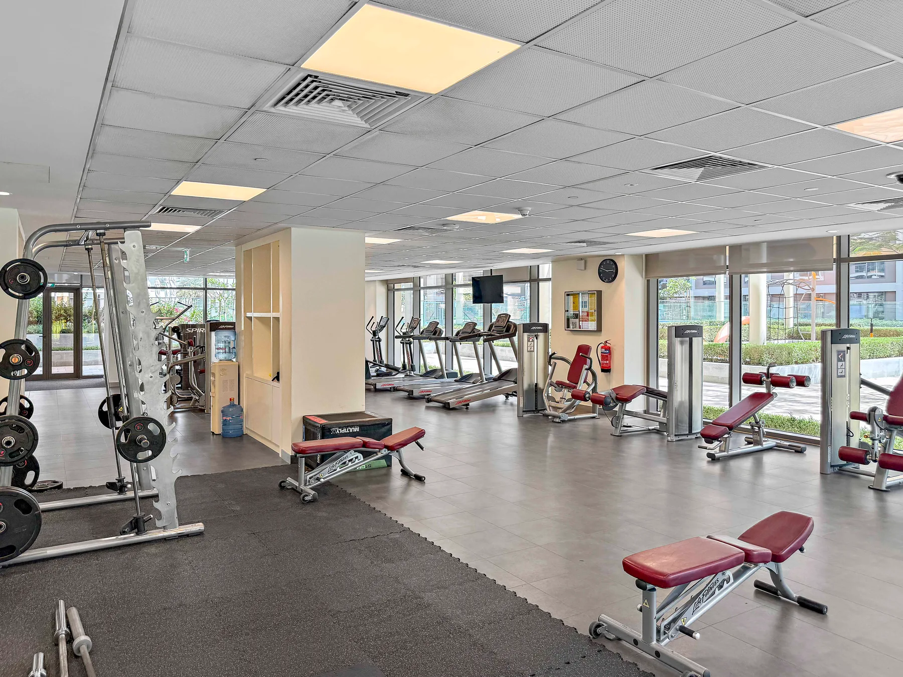 Un gimnasio con máquinas de ejercicio, pesas y bancos.