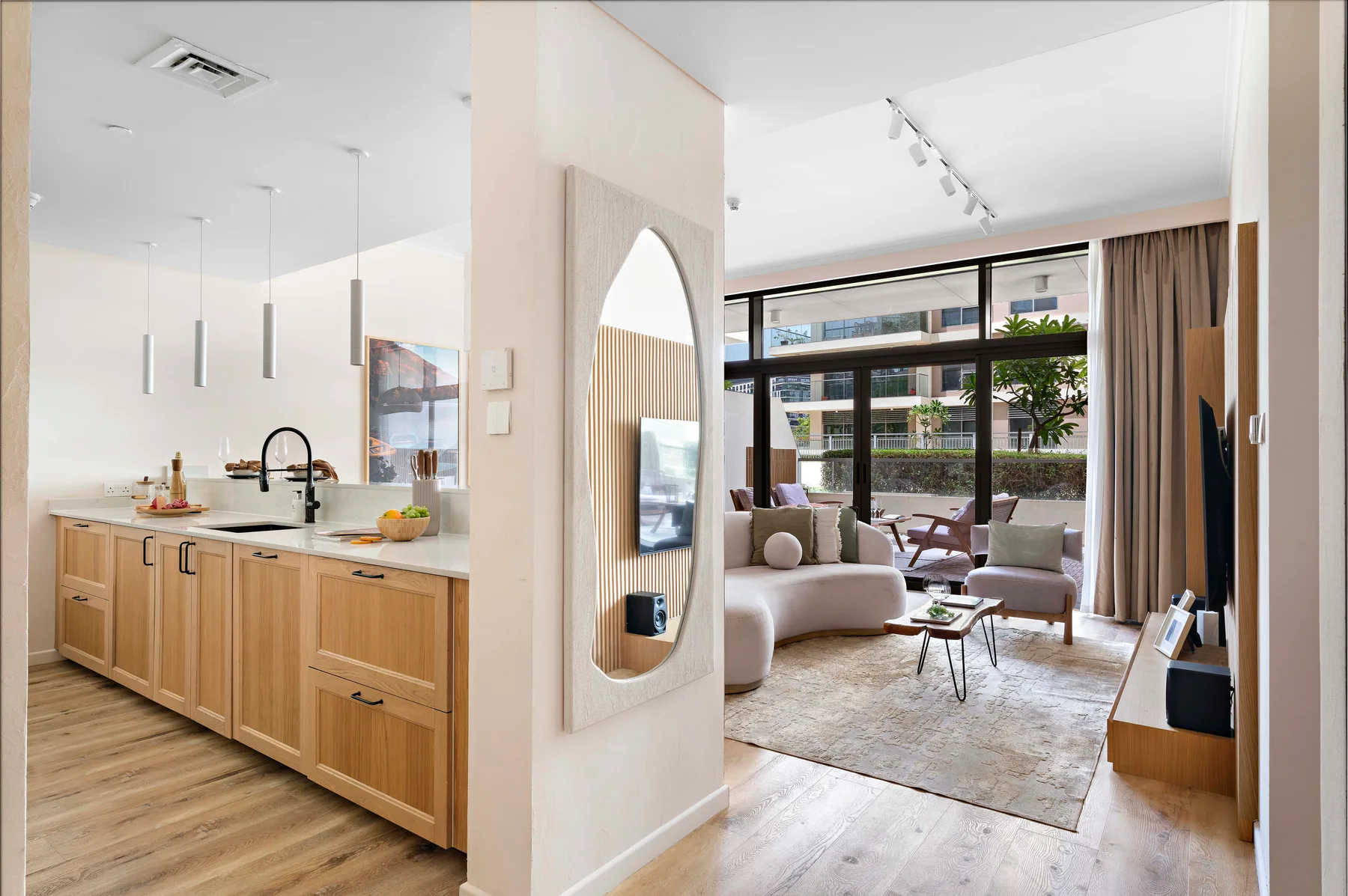 Sala de estar y cocina de concepto abierto, con grandes ventanas y muebles de madera clara.