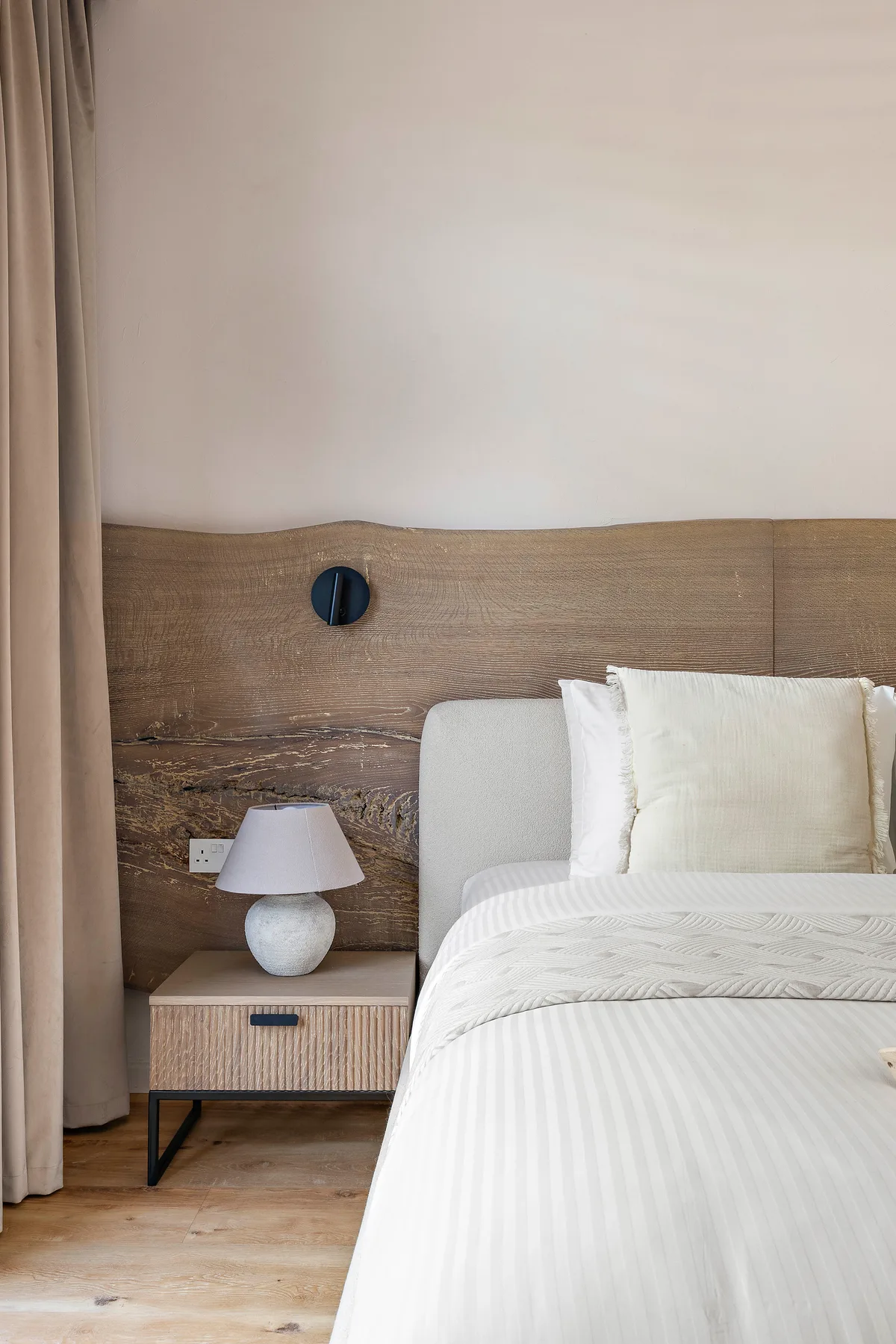Un dormitorio con una cama bien tendida junto a una pequeña mesita de noche.