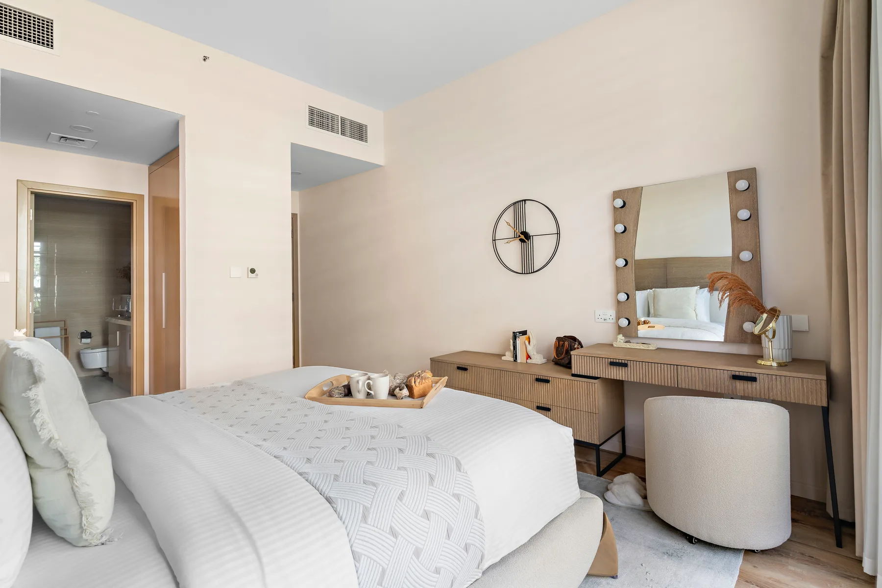 Un dormitorio luminoso con una cama tendida y un tocador junto a la pared.