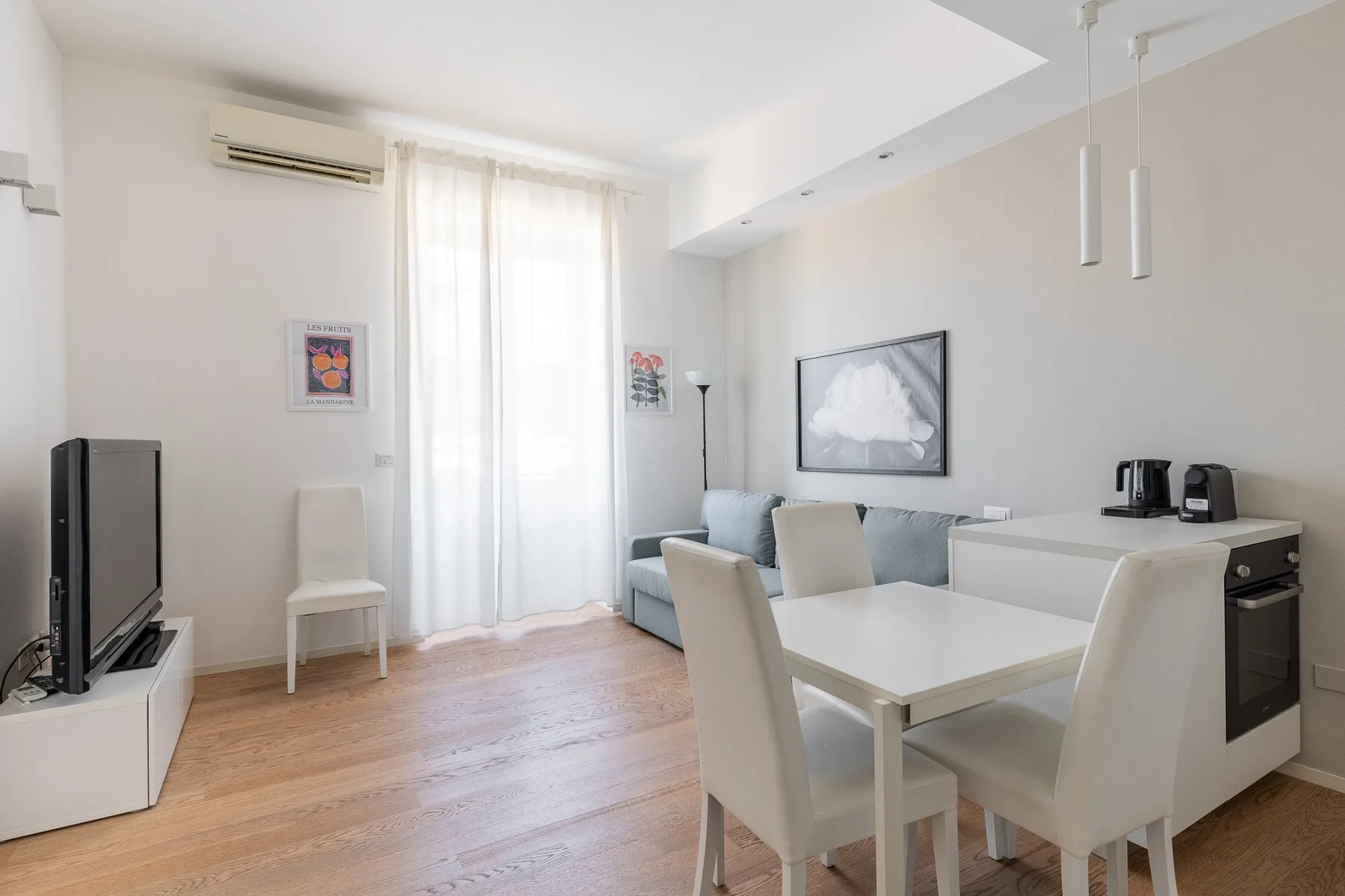 Una luminosa sala de estar y comedor con sofá, televisor y mesa de comedor.