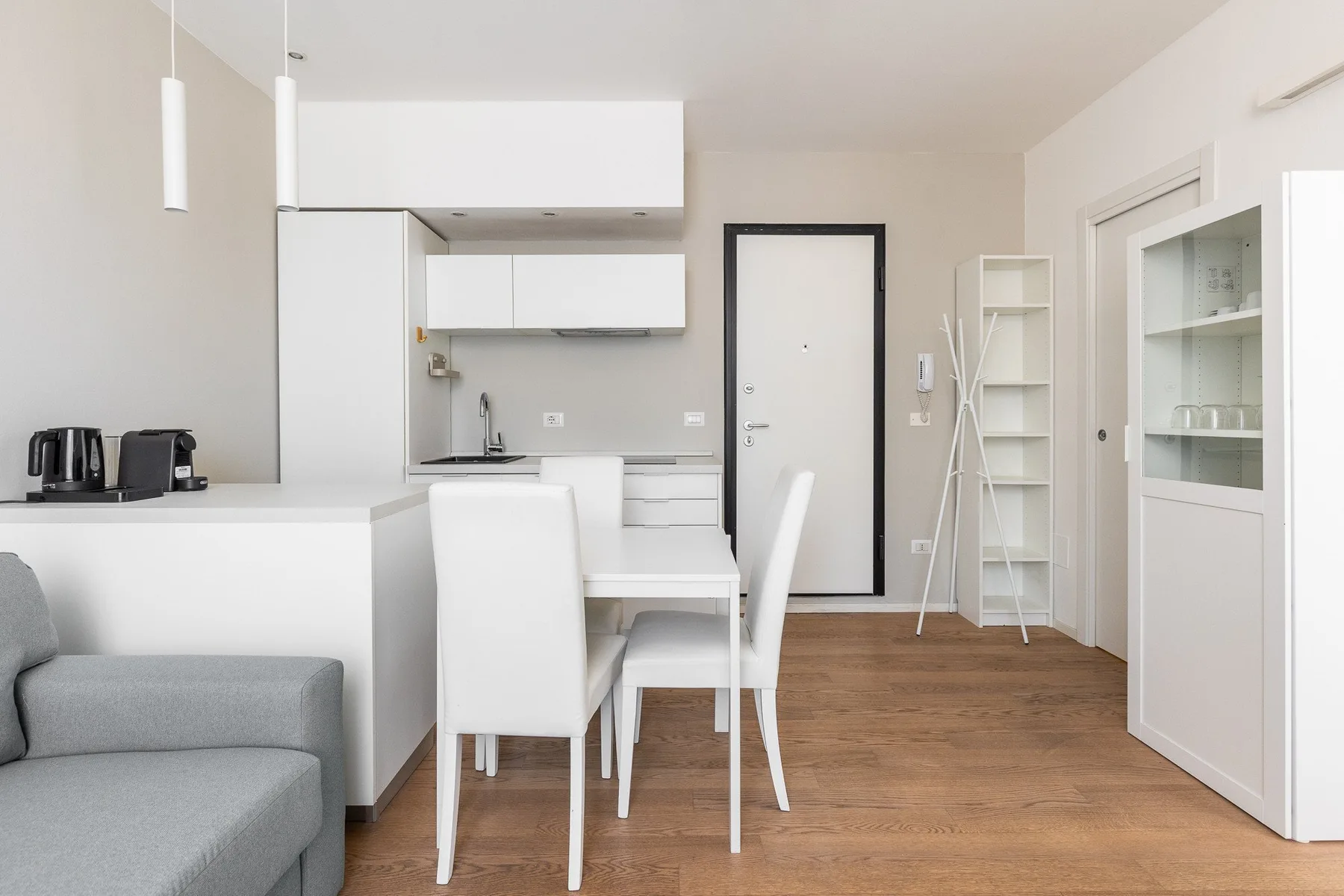 Una cocina y comedor luminosos con gabinetes blancos y una mesa.