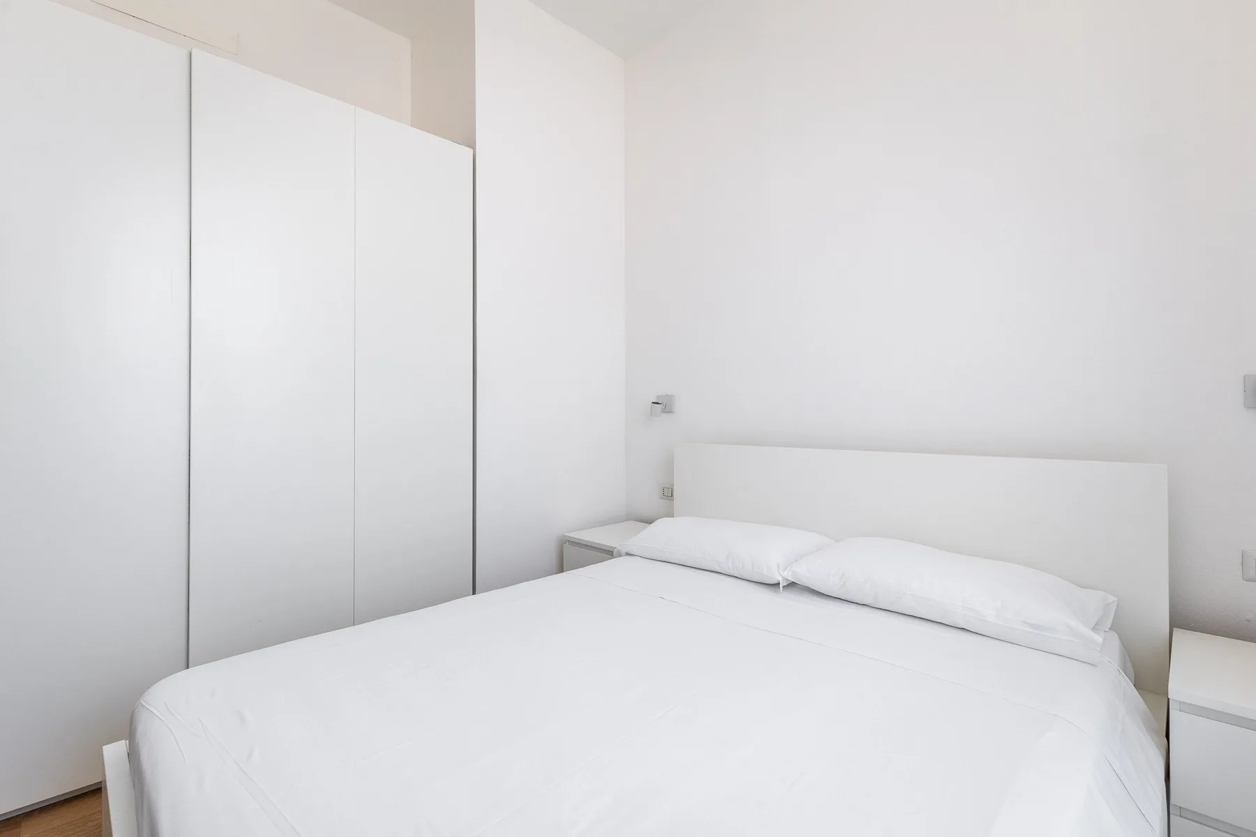 Un dormitorio luminoso con una cama bien hecha y armarios empotrados.