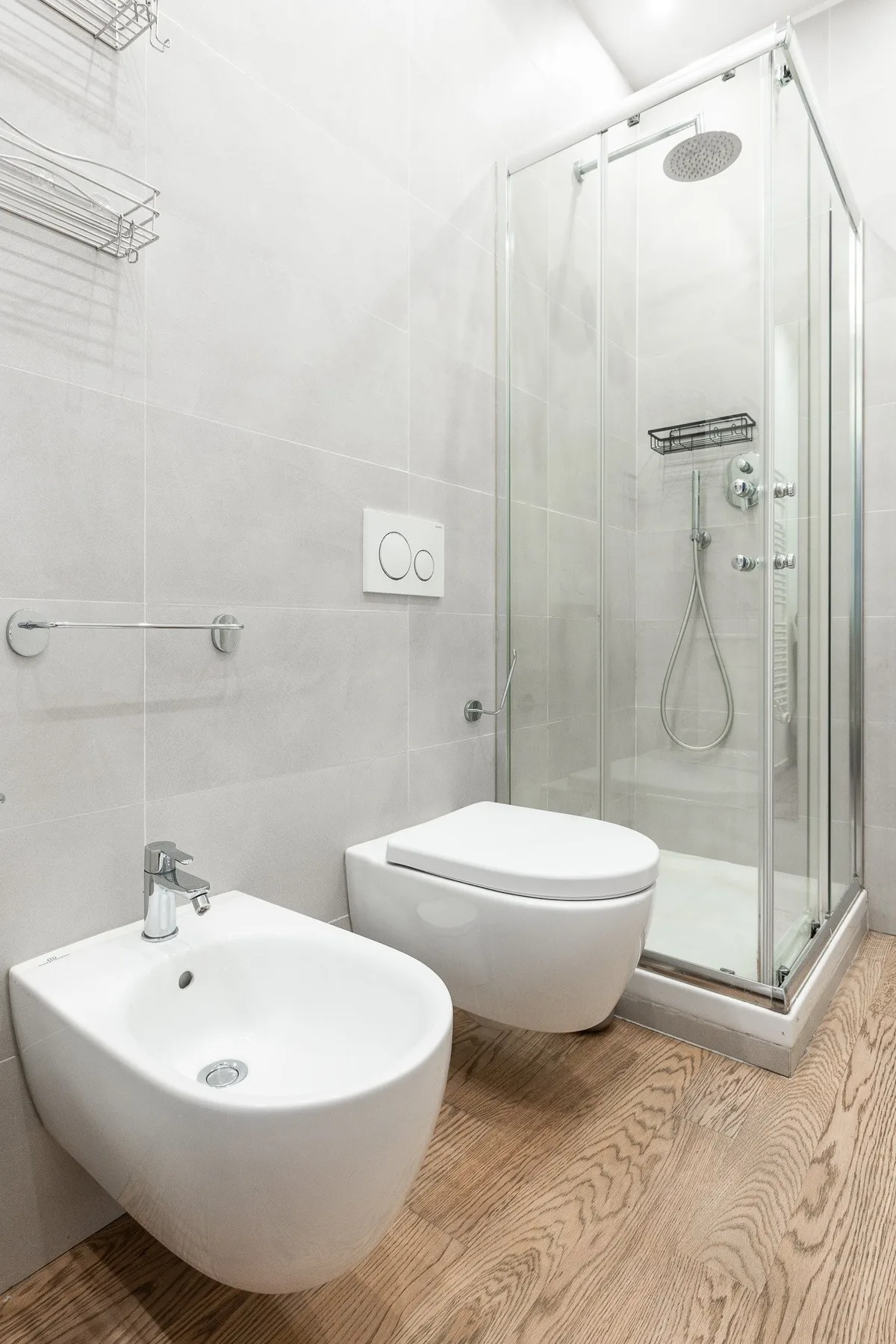 Un baño luminoso con una ducha de vidrio y sanitarios blancos.