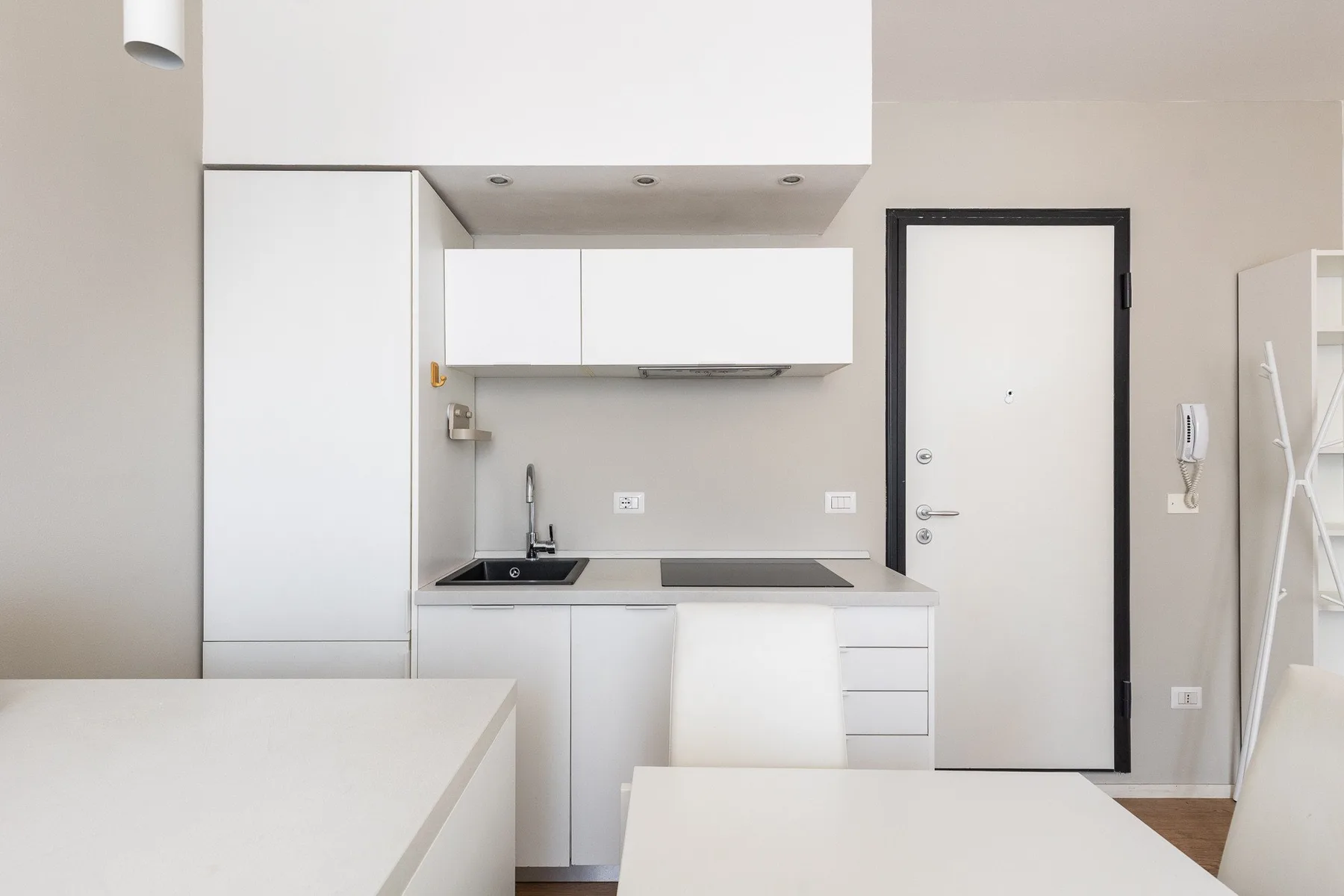 Una cocina compacta con gabinetes blancos, un fregadero y una encimera.