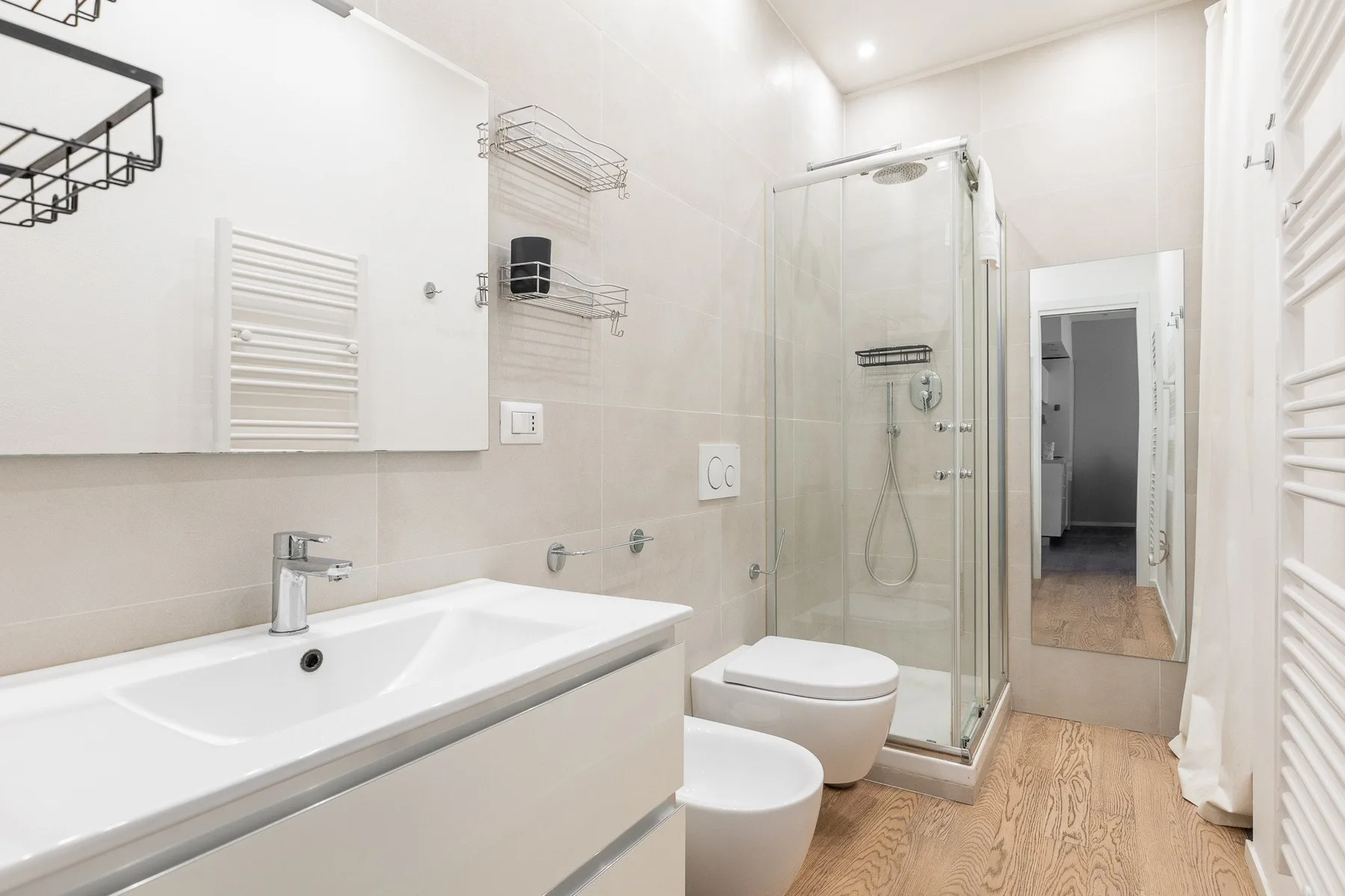 Un baño luminoso con lavabo, ducha y una puerta hacia el pasillo.