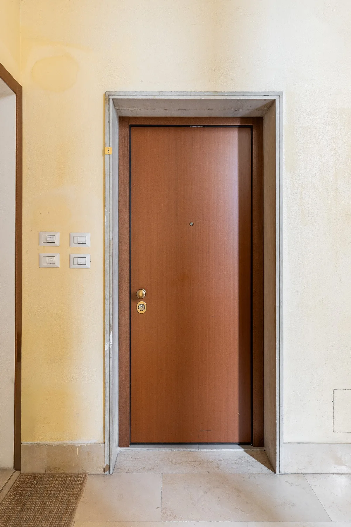 Una puerta de madera cerrada está integrada en una pared interior de color claro.
