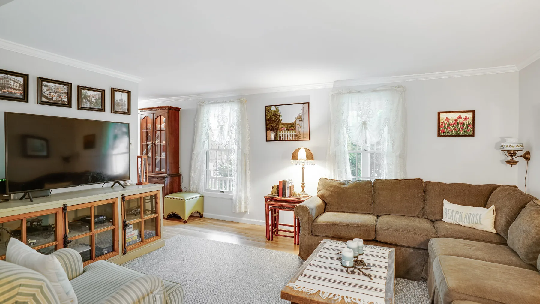 A bright living room with a brown sectional sofa and a television.