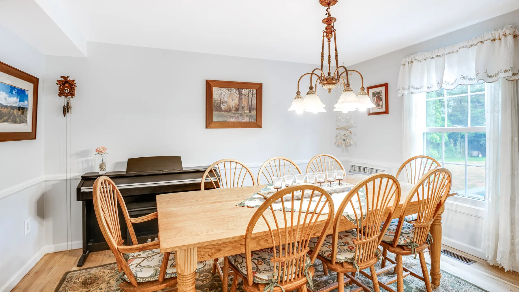 A bright dining room with a wooden table and several chairs beside a large window.