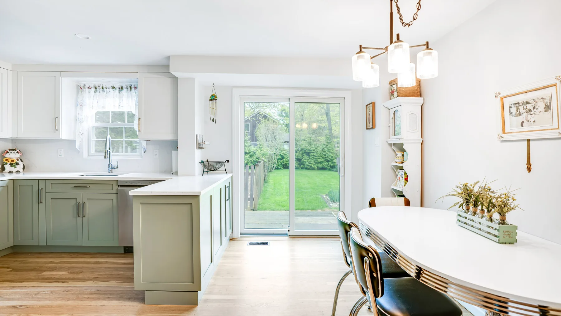A bright kitchen and dining area with pale cabinetry and a garden view through glass doors.