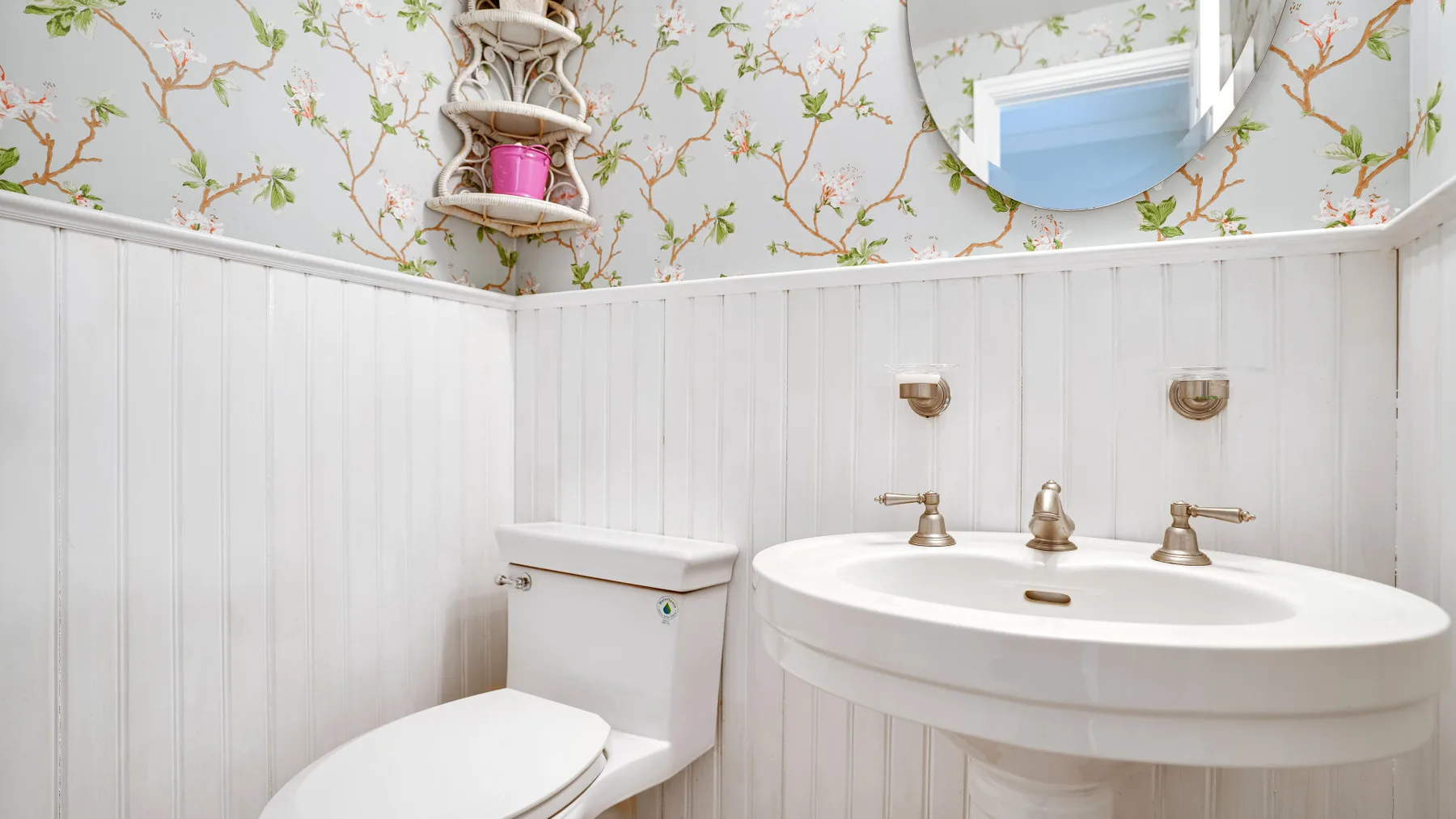 A bathroom with a sink, toilet, and floral wallpaper.