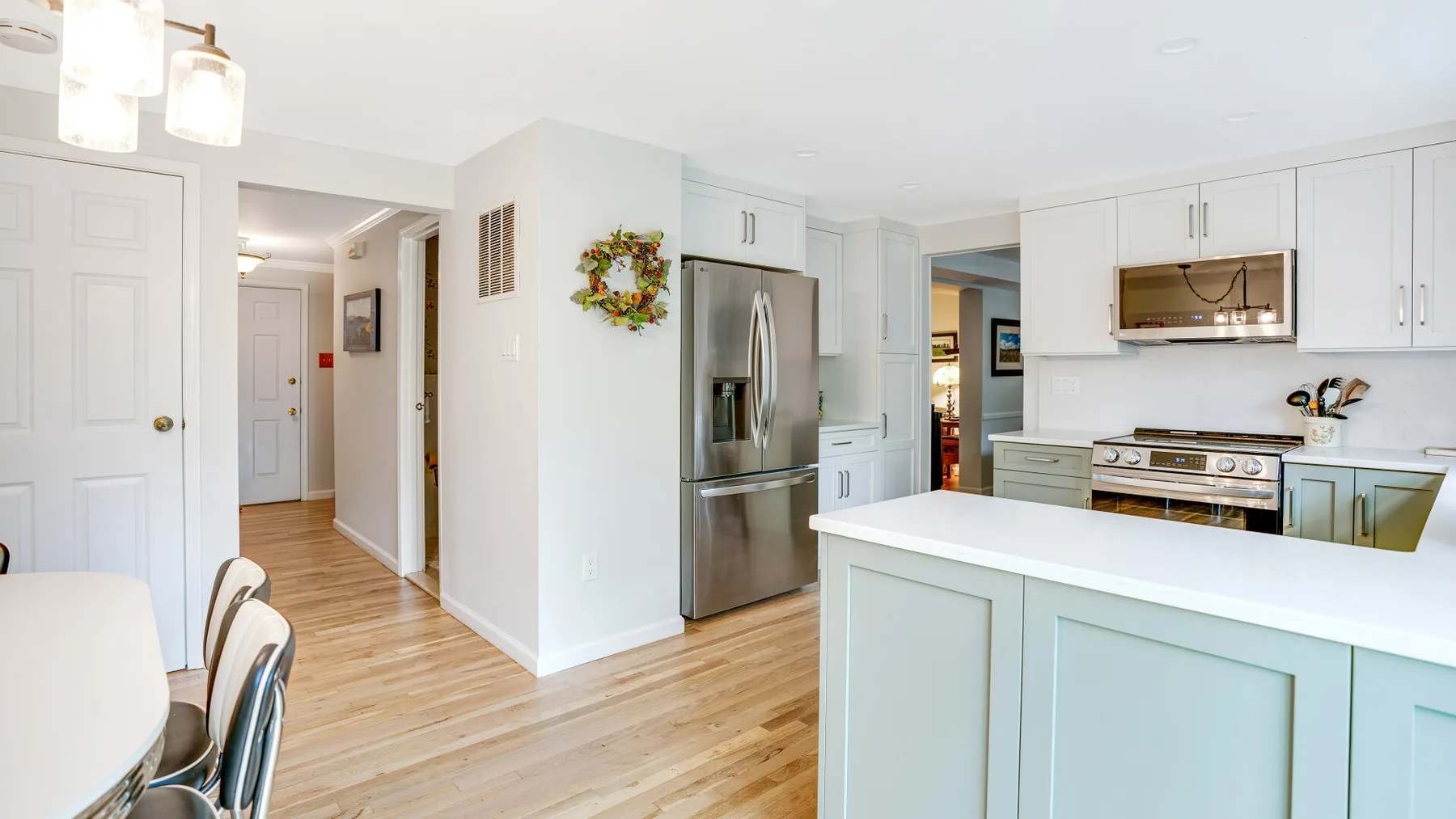 A bright kitchen with white cabinets, stainless steel appliances, and a breakfast counter.