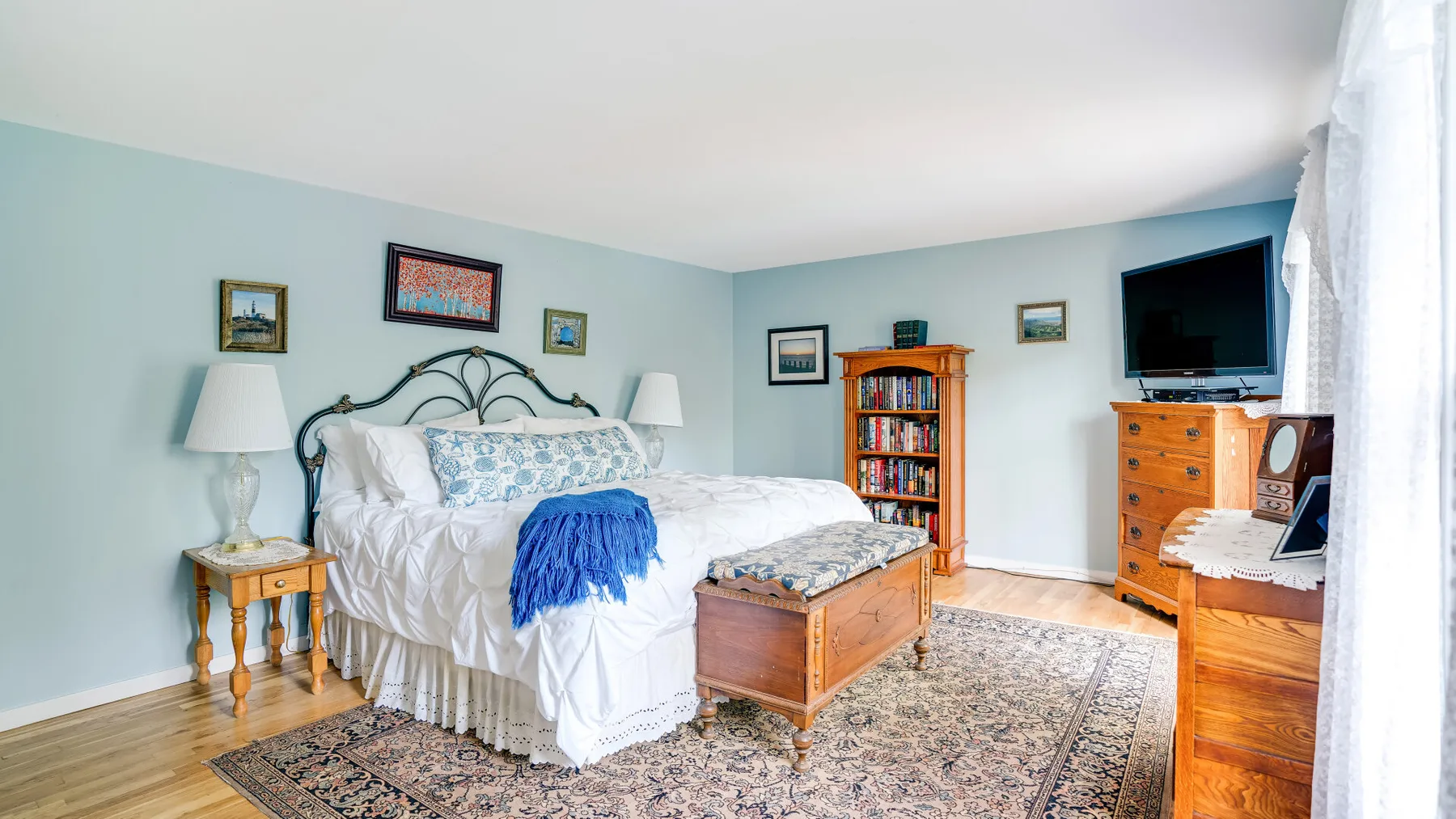 A bedroom with a bed, wooden furnishings, and a patterned rug.