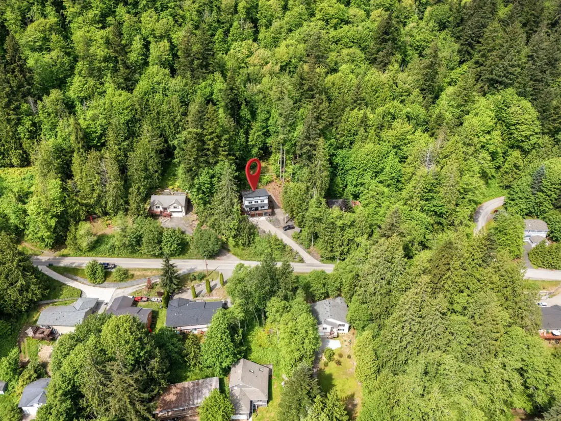 Una vista aérea muestra varios edificios junto a una carretera, rodeados de árboles frondosos.