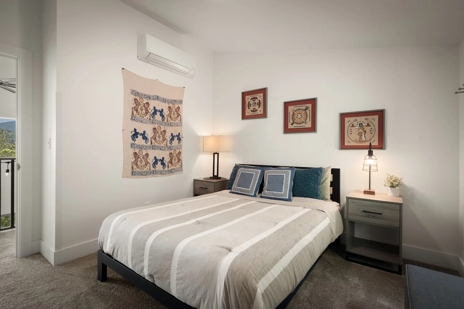 Un dormitorio con una cama tendida, mesitas de noche y cuadros en la pared.