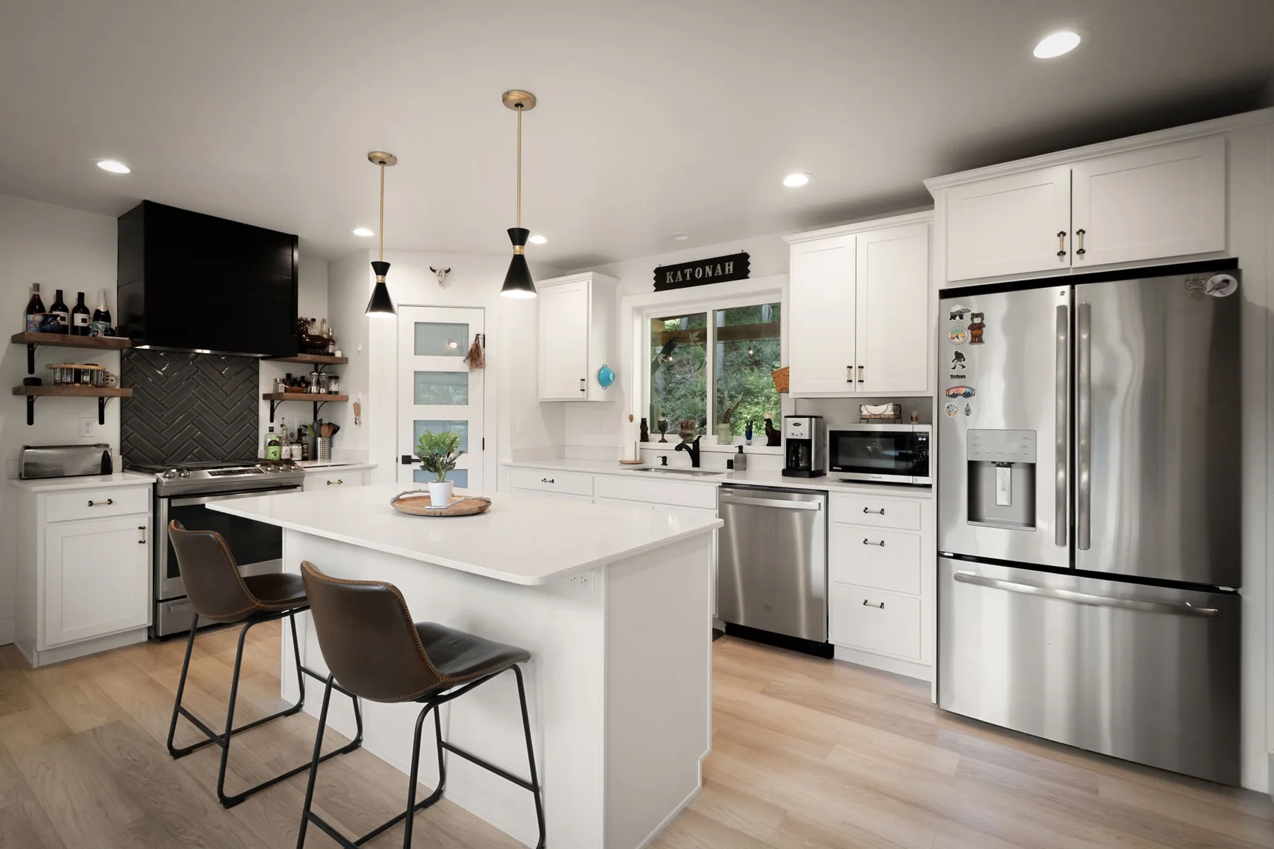 Una cocina luminosa con isla central, gabinetes blancos y electrodomésticos de acero inoxidable.
