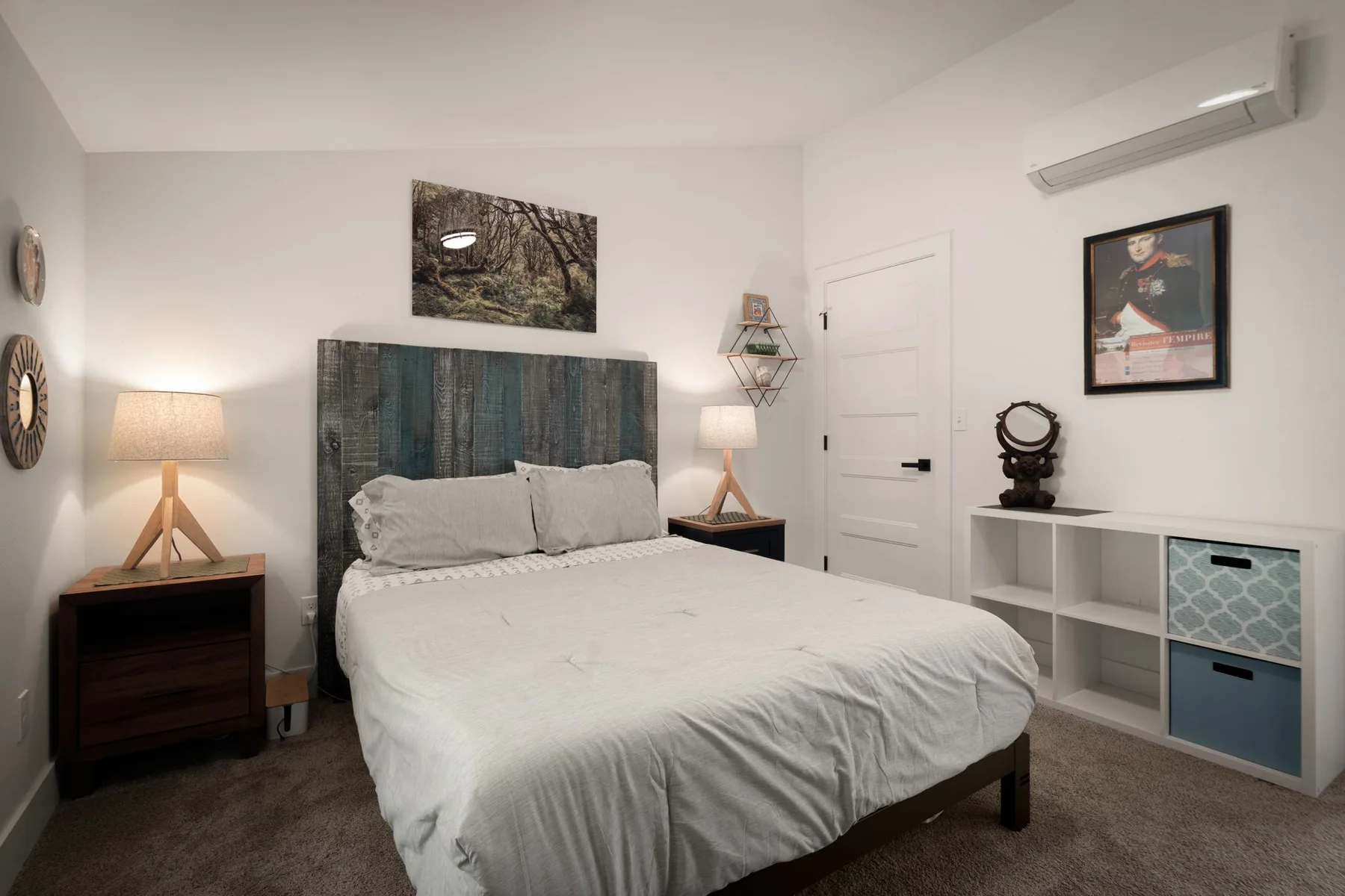 Un dormitorio con una cama, mesitas de noche y estanterías blancas.