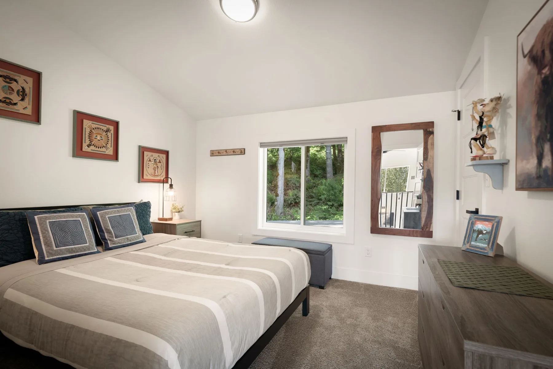 Un dormitorio con una cama bien tendida y una ventana con vistas a la vegetación.
