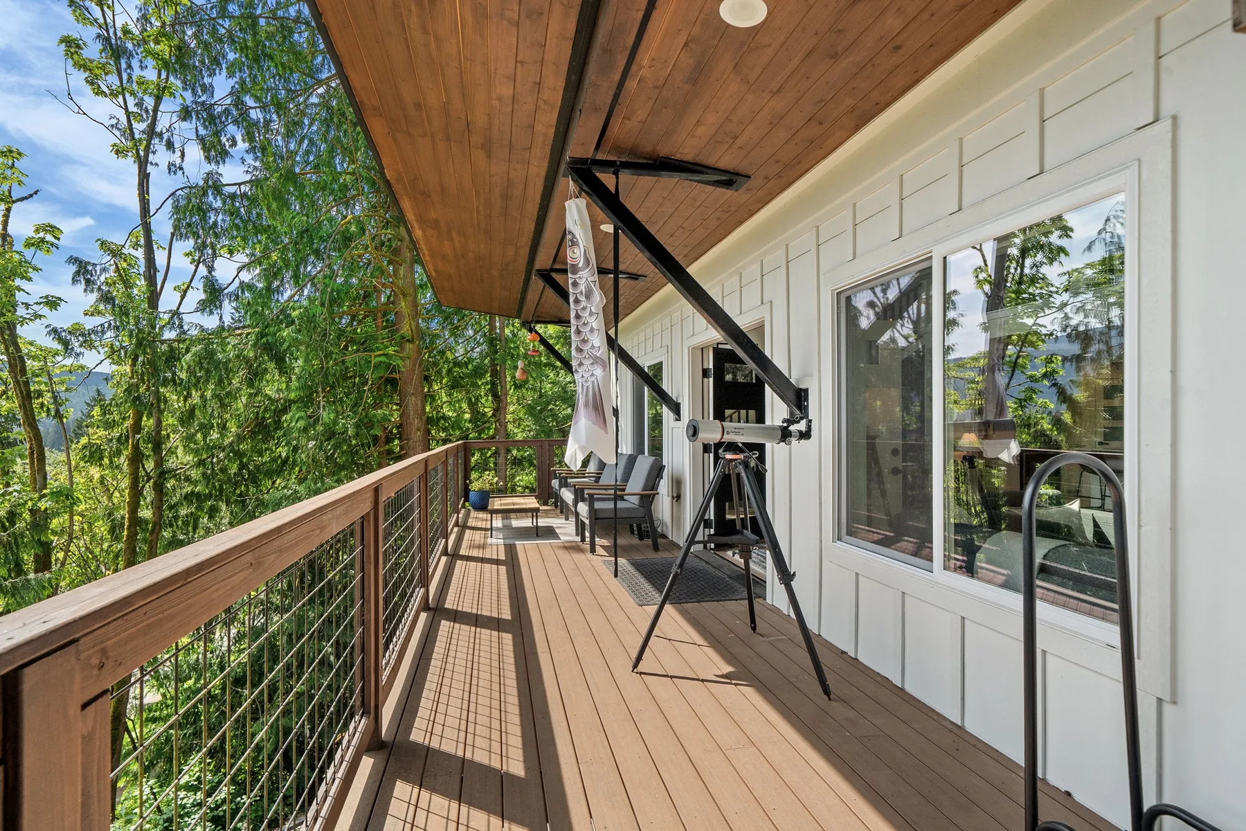 Una terraza de madera cubierta con asientos al aire libre da a árboles frondosos.
