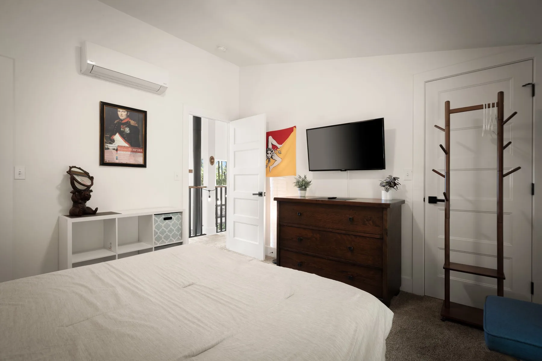 Un dormitorio con cama, cómoda y televisor montado en la pared.
