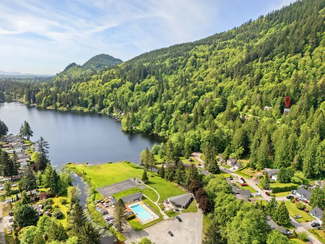 Vista aérea de una zona recreativa junto a un lago, rodeada de colinas boscosas.