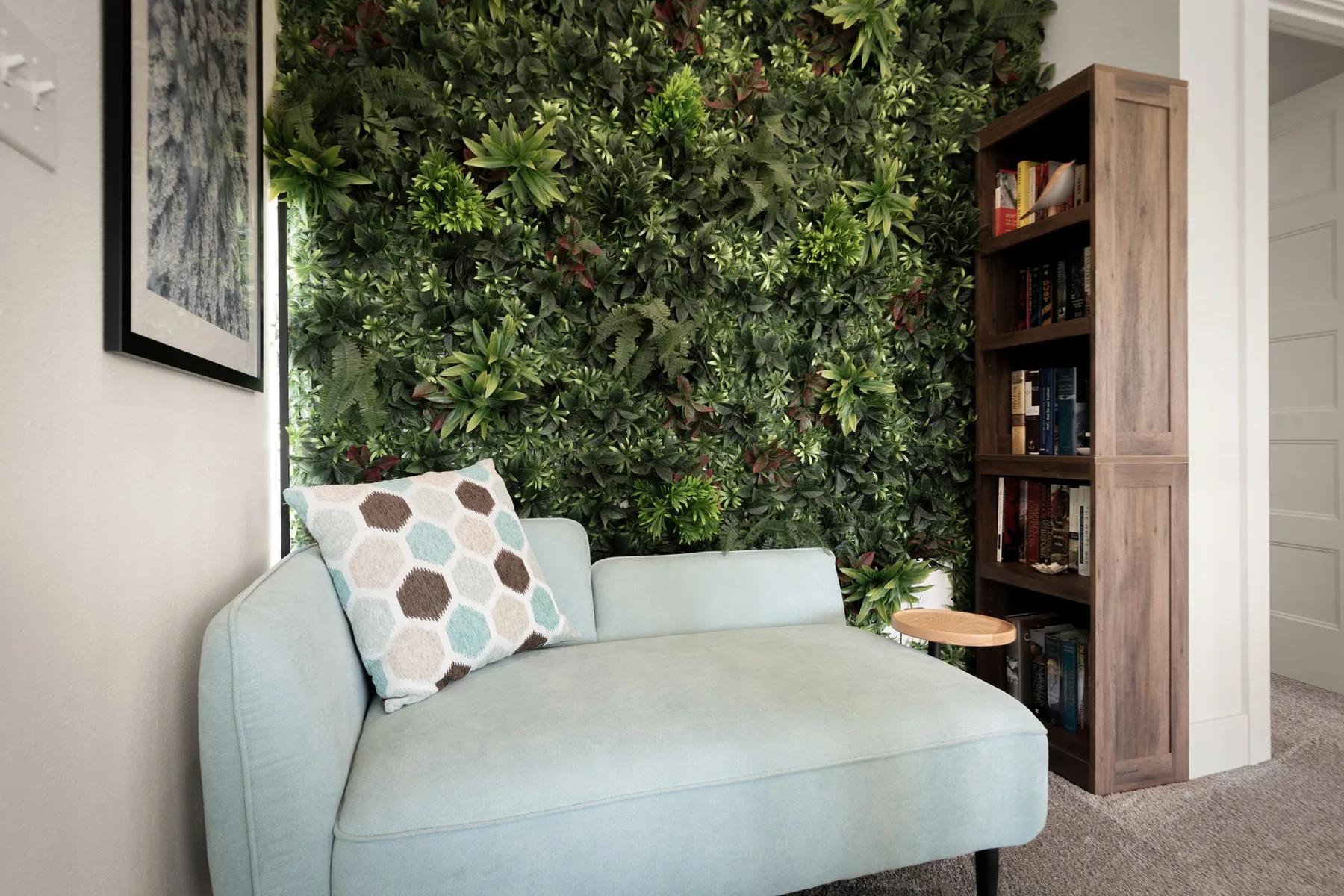 Una zona de asientos azul claro frente a una pared cubierta de plantas verdes.