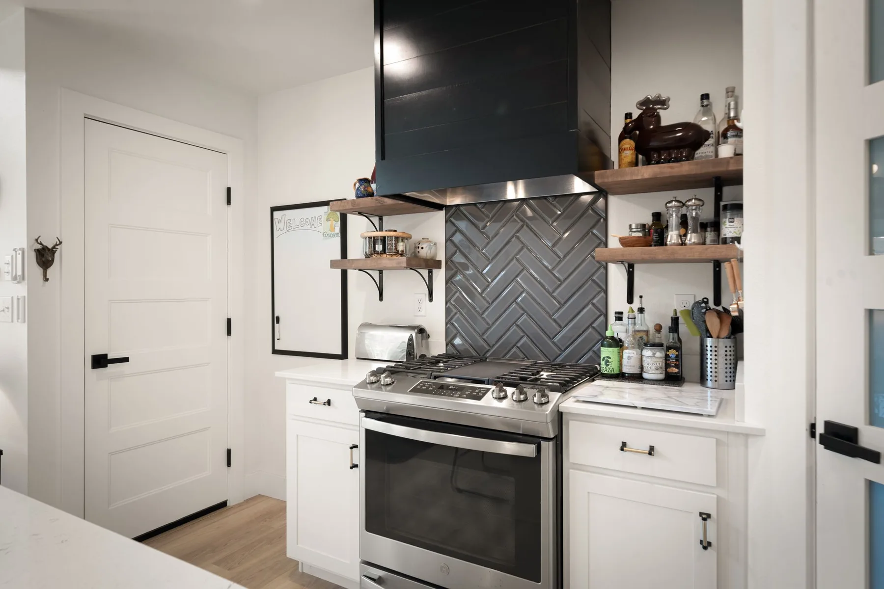 Una cocina luminosa con una estufa de acero inoxidable bajo estantes abiertos.