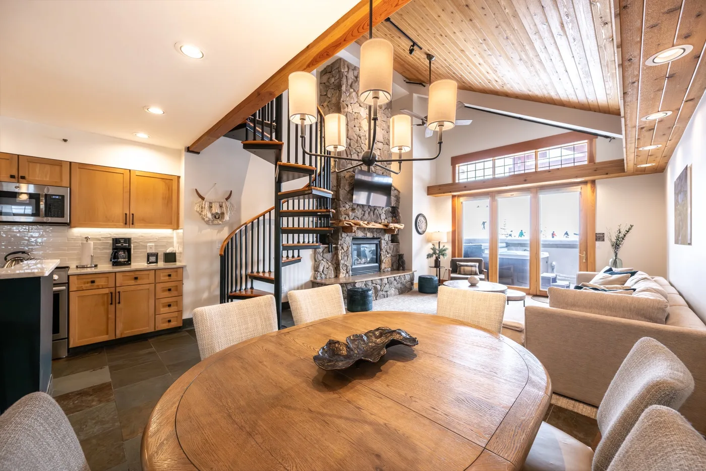 An open-plan living and dining room with a kitchen and a large wooden table.