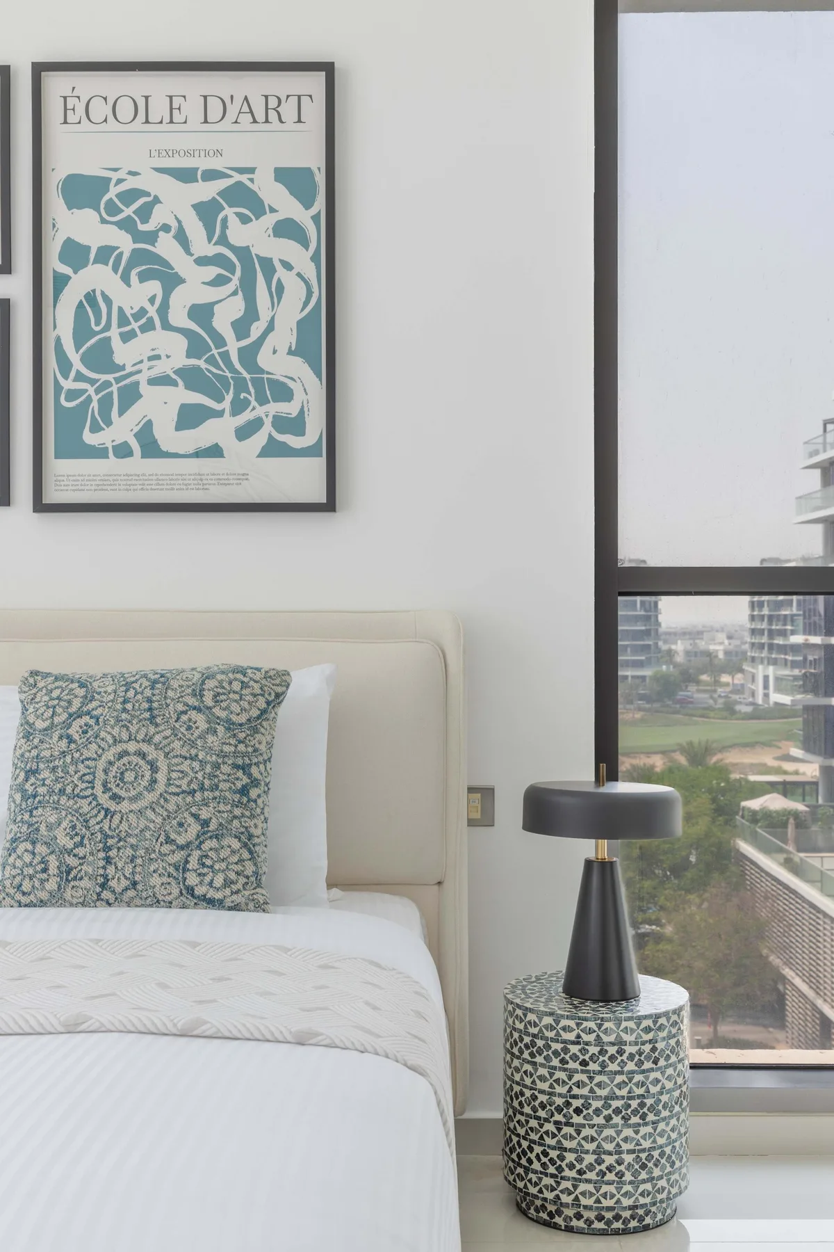 Un dormitorio con una cama estampada junto a una ventana grande.