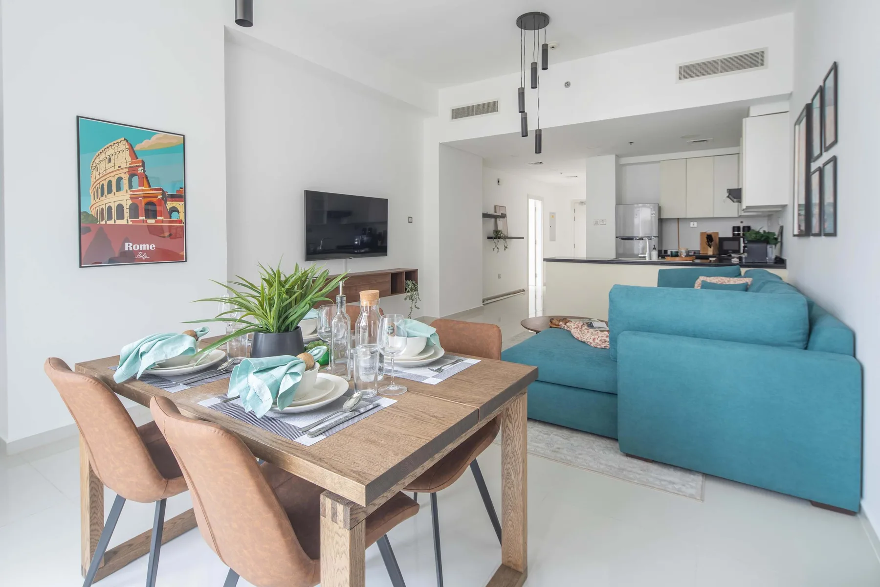 Una luminosa sala-comedor de planta abierta con una mesa y asientos color turquesa.