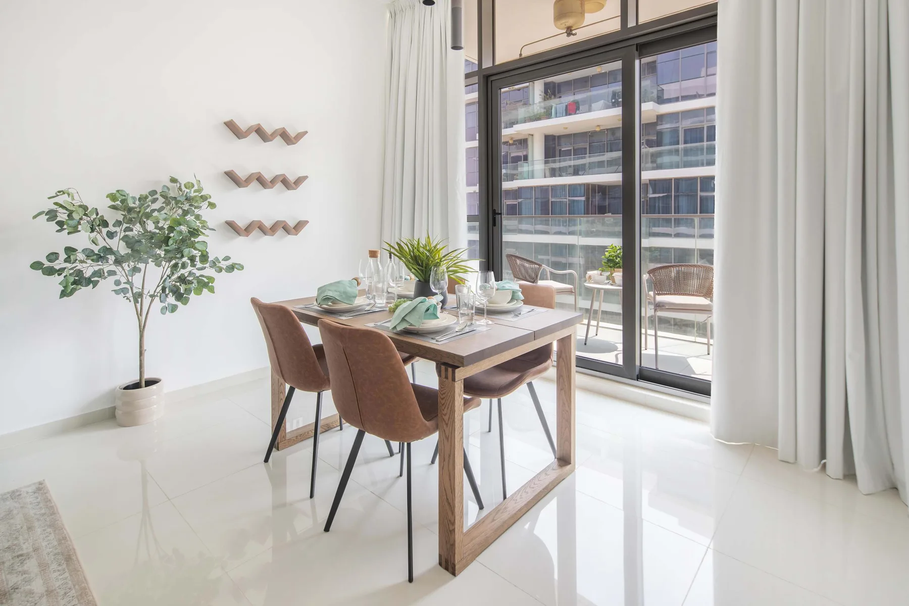 Un comedor luminoso con una mesa de madera junto a grandes ventanales y cortinas.