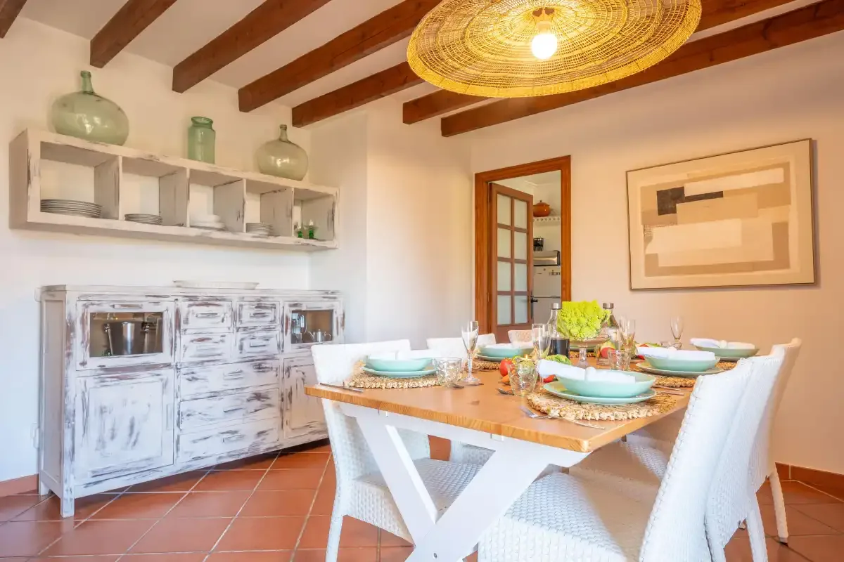 A dining room with a wooden table set with dishes beneath a woven pendant light.