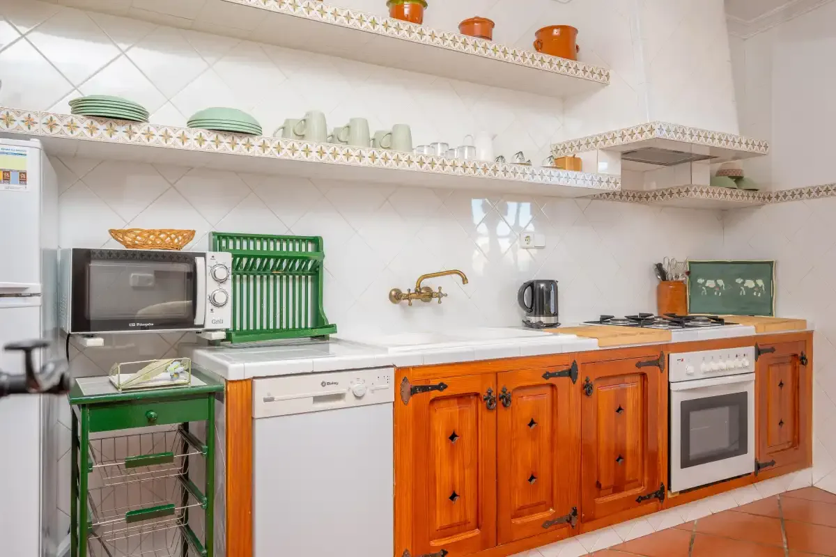A kitchen with orange wooden cabinets, open shelves, and countertop appliances.